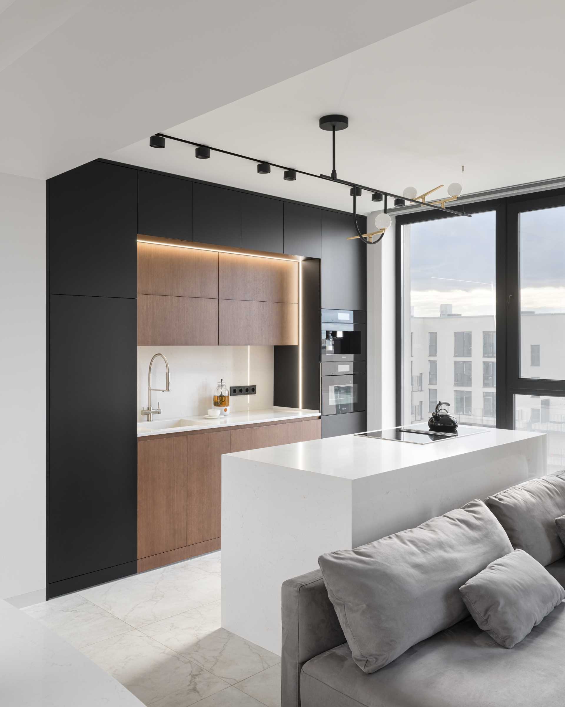 A modern kitchen with black, wood, and white cabinets, and hidden lighting.