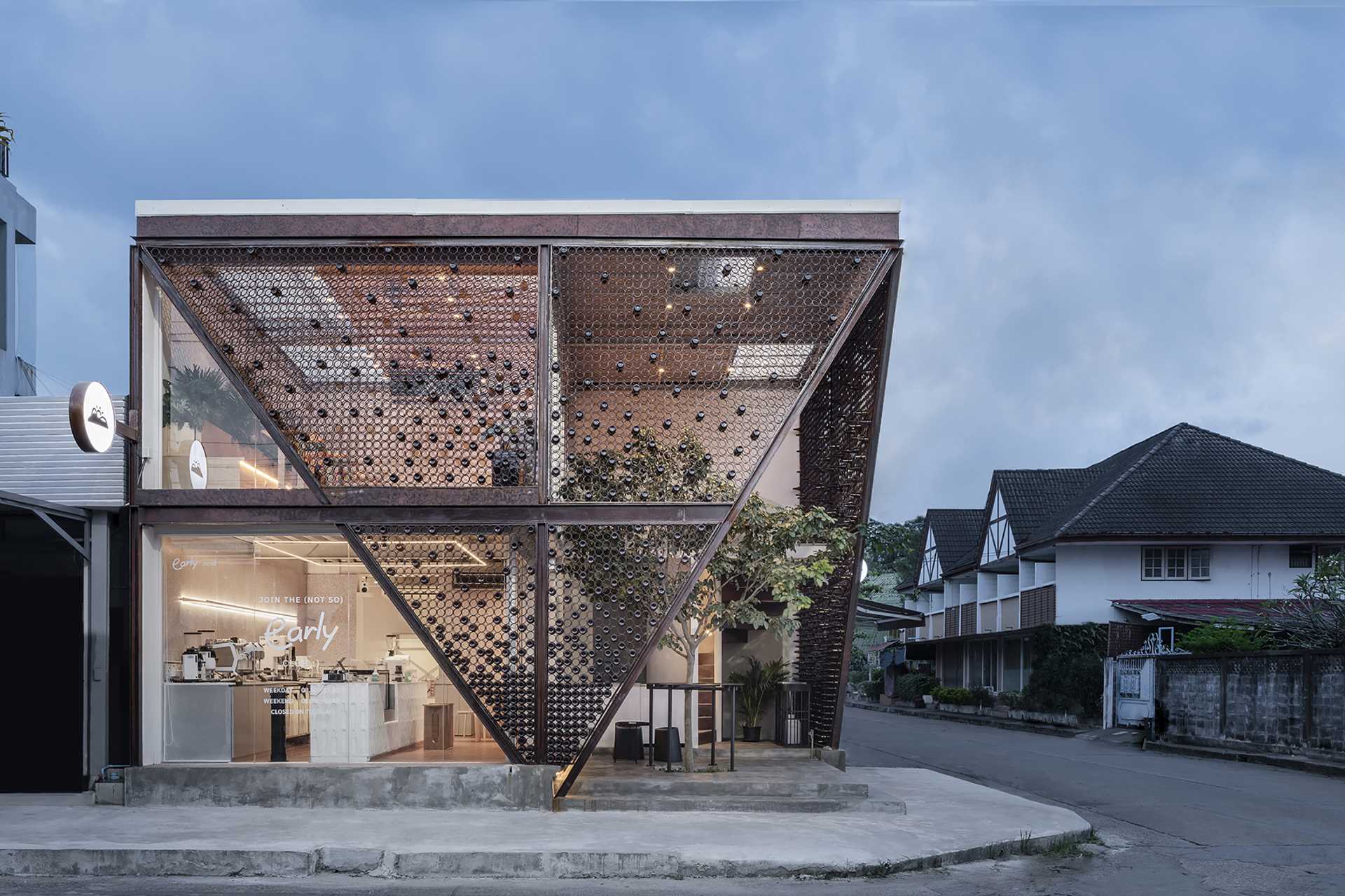 A modern cafe with a facade that features metal rings that hold recycled beer bottles.