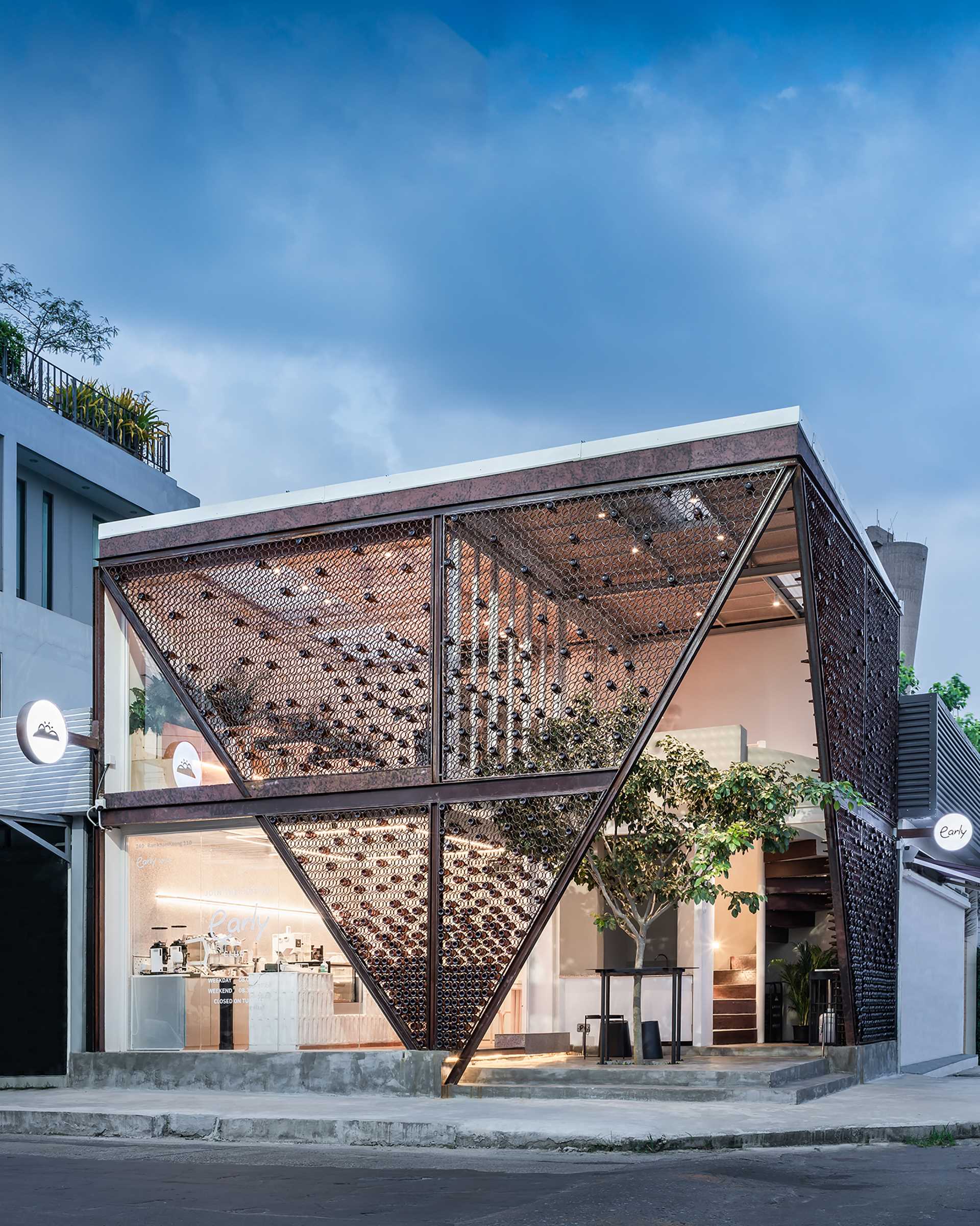 A modern cafe with a facade that features metal rings that hold recycled beer bottles.