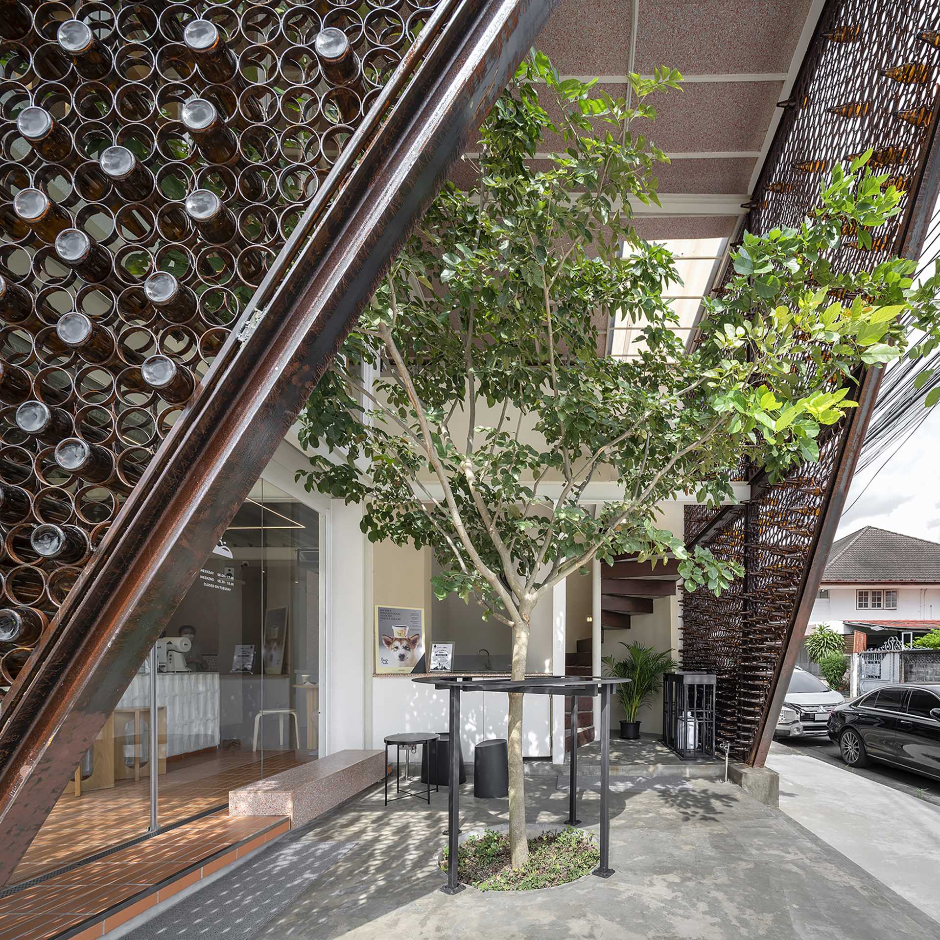 A modern cafe with a facade that features metal rings that hold recycled beer bottles.