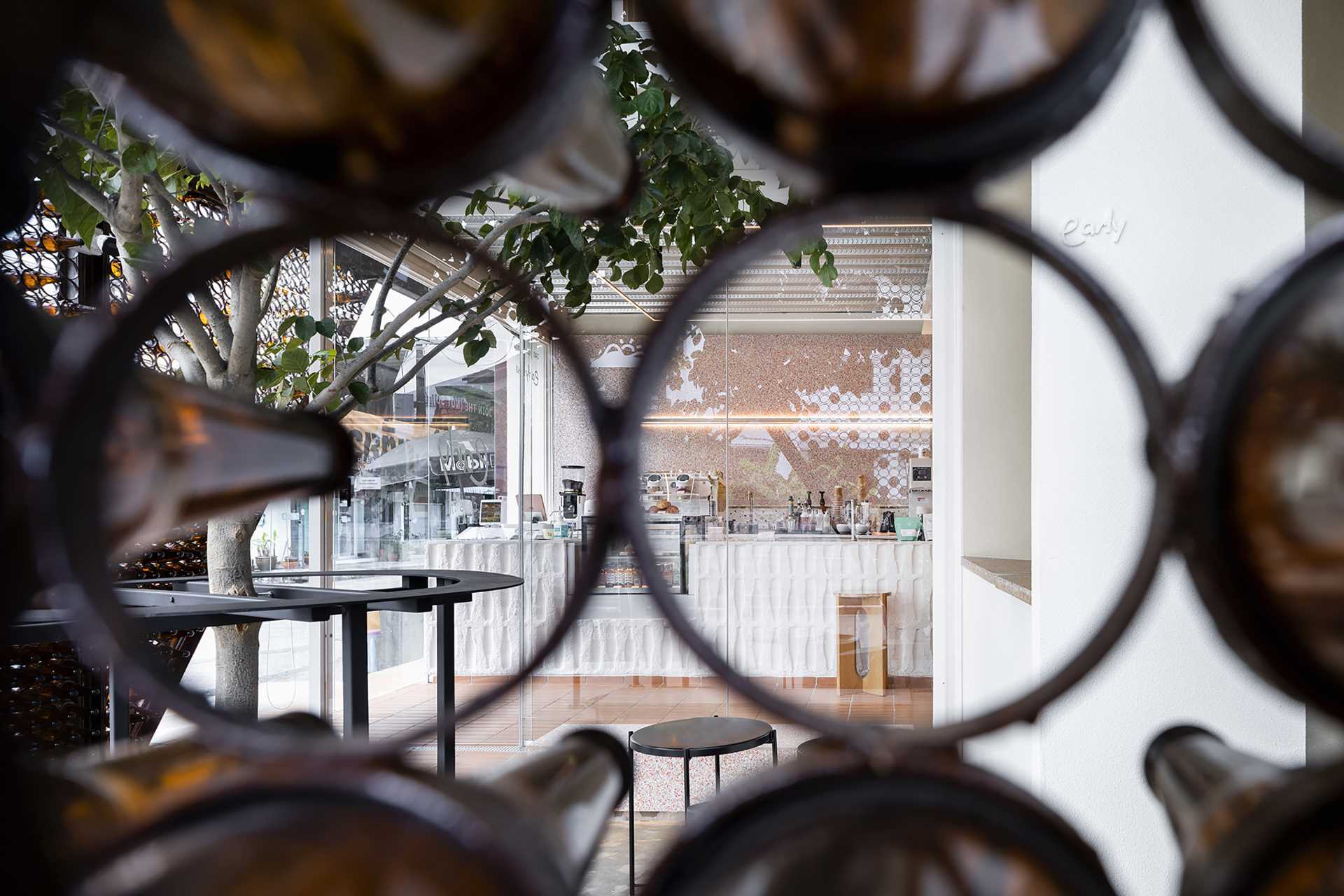 A modern cafe with a facade that features metal rings that hold recycled beer bottles.