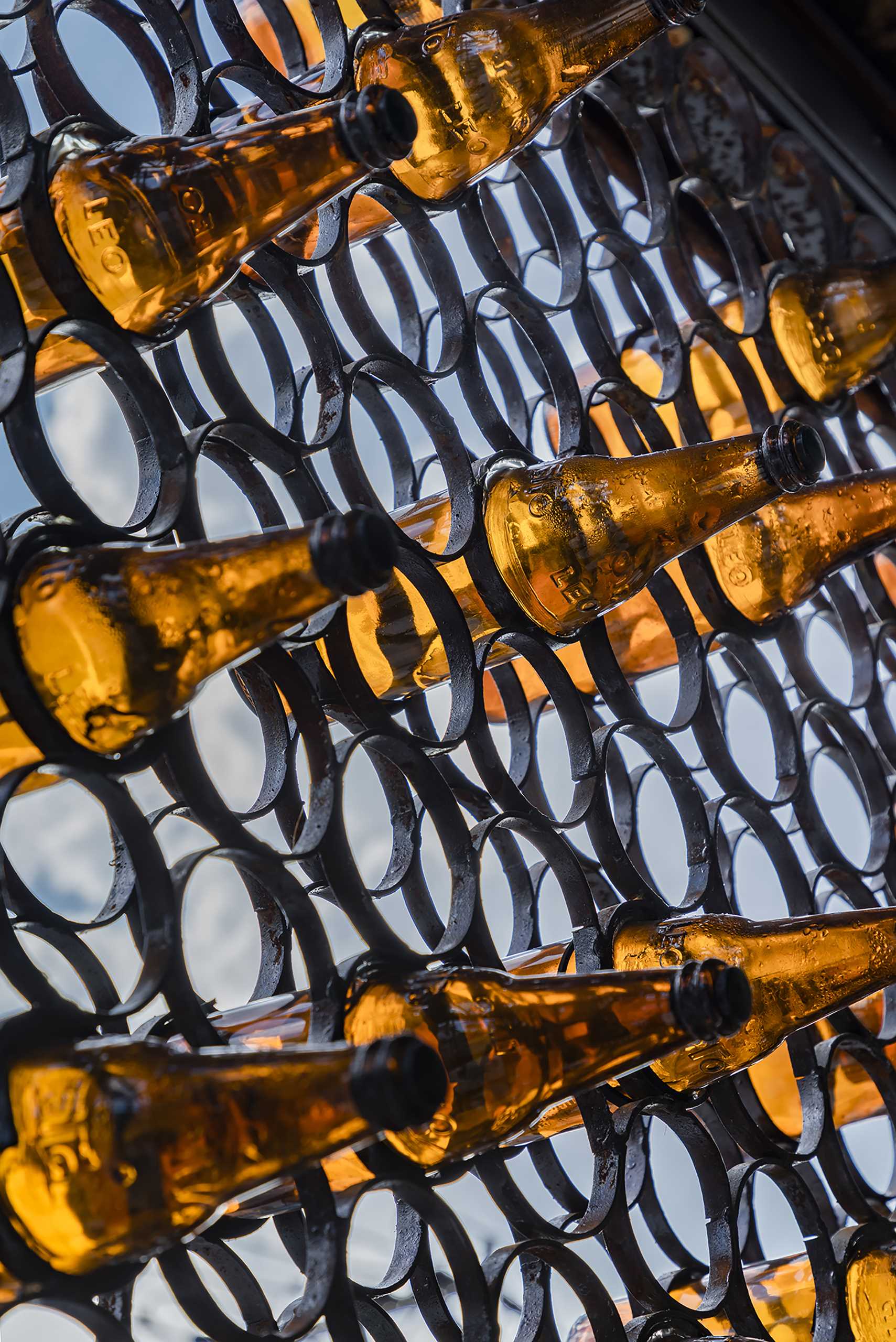 A modern cafe with a facade that features metal rings that hold recycled beer bottles.