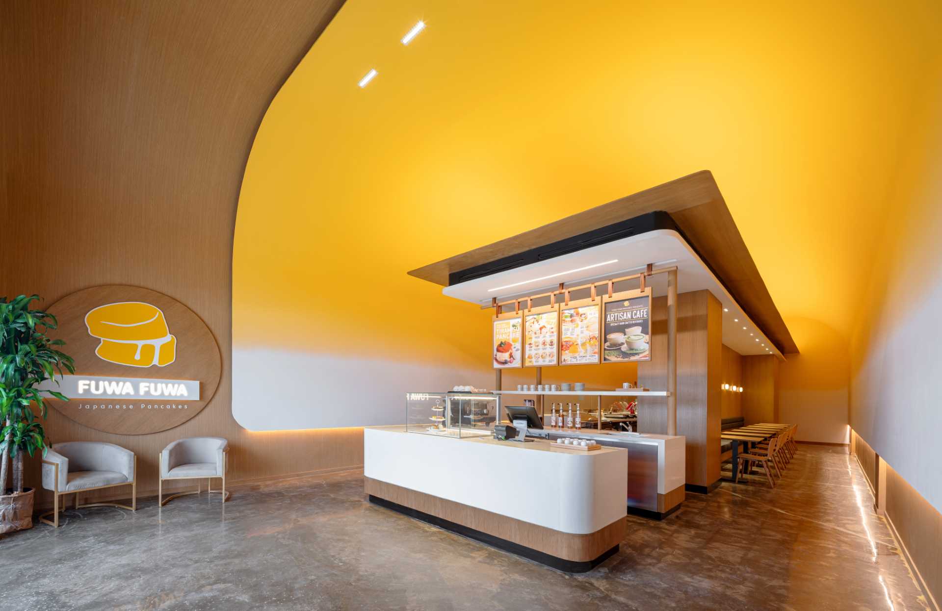 Visitors to this modern cafe are greeted by the soft curve and bright yellow of the high ceiling as it frames a modern temple-like structure.