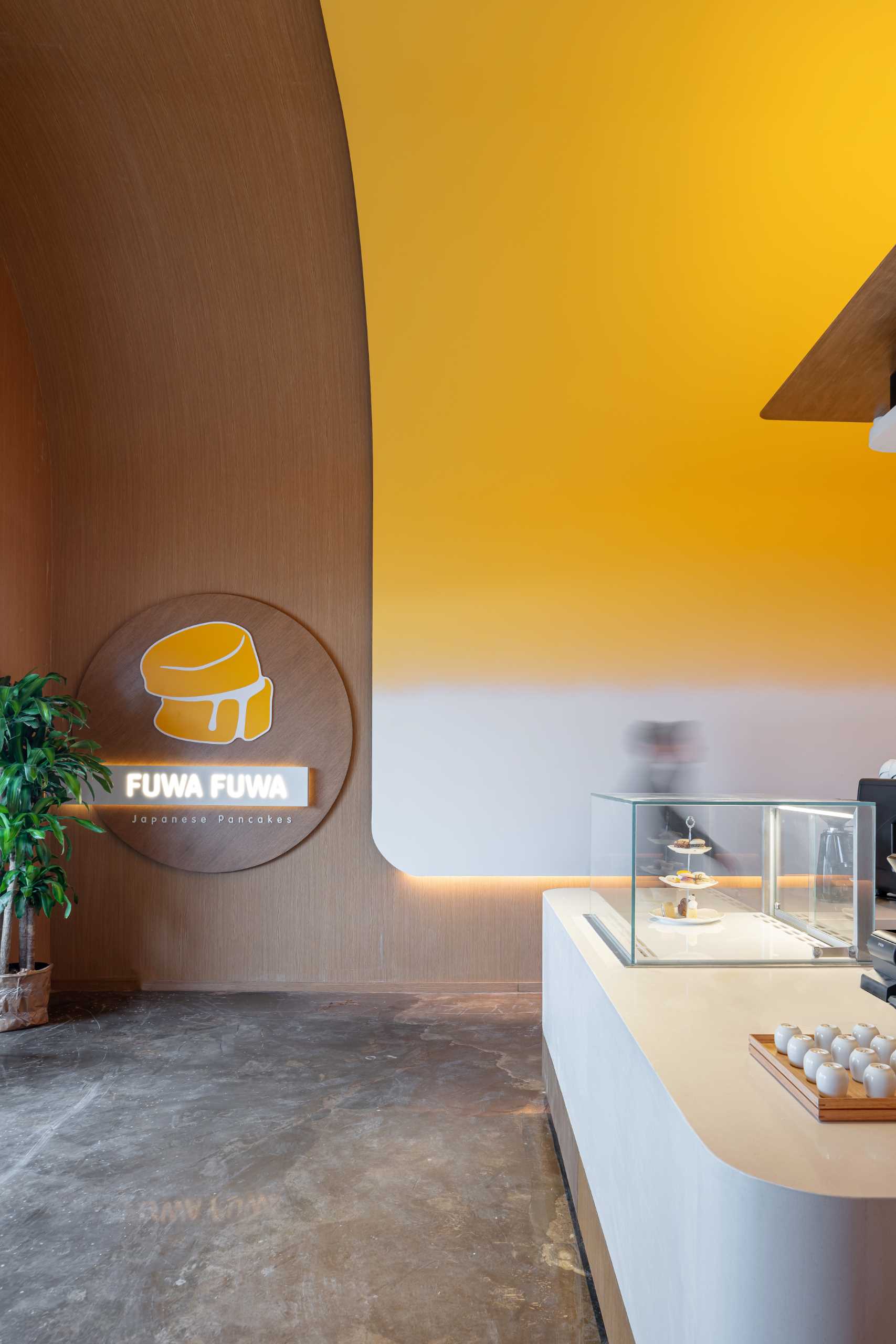 A modern cafe with hidden lighting and a curved yellow ceiling.