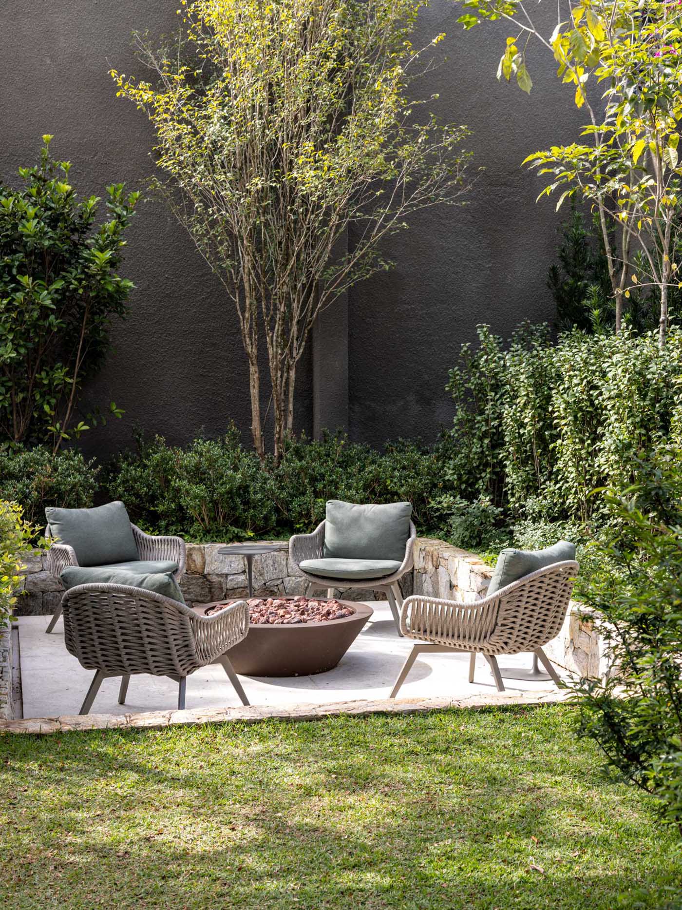 A modern garden with a sunken seating area that includes a firepit.