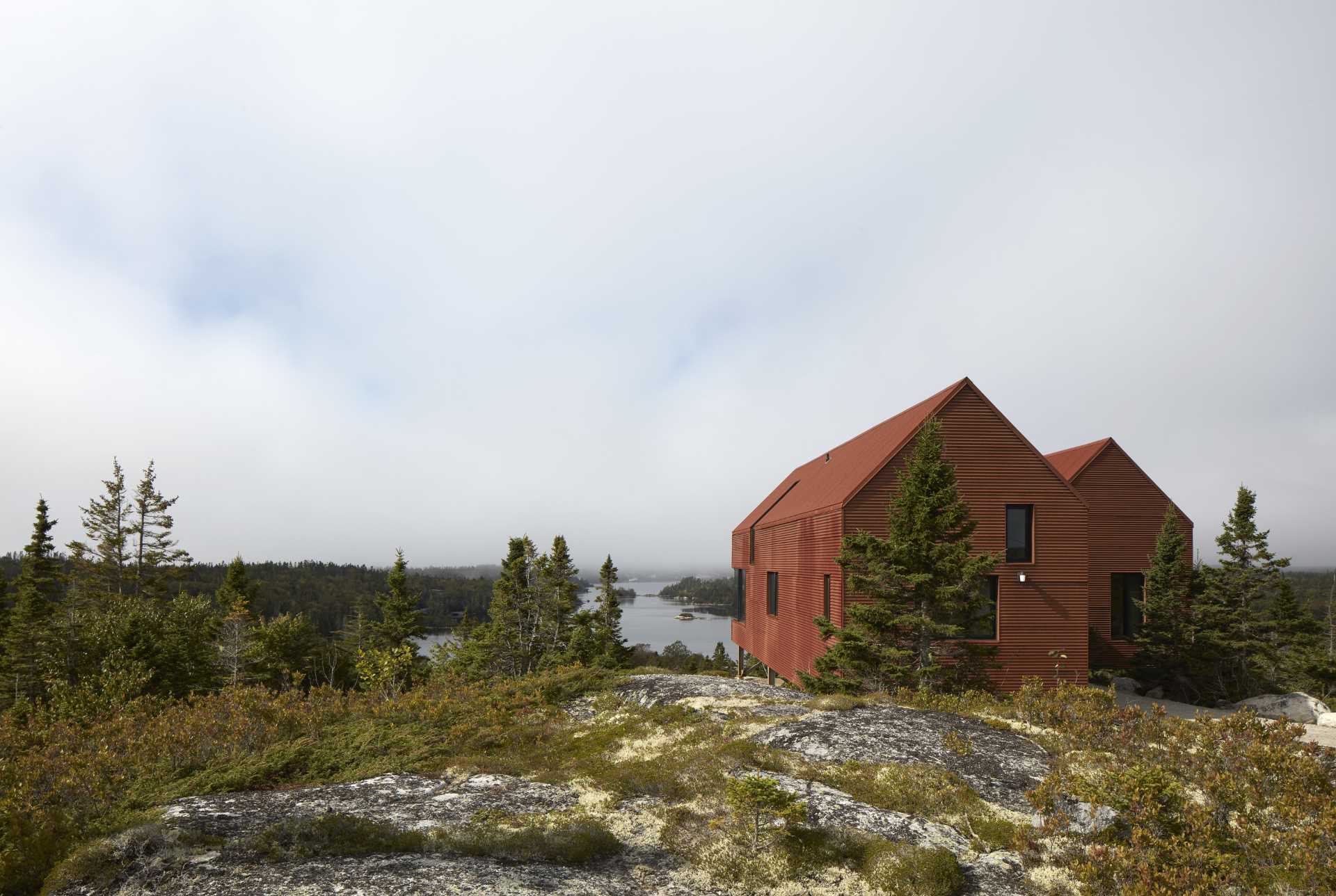 A modern house with weathered corrugated steel exterior and black window frames.
