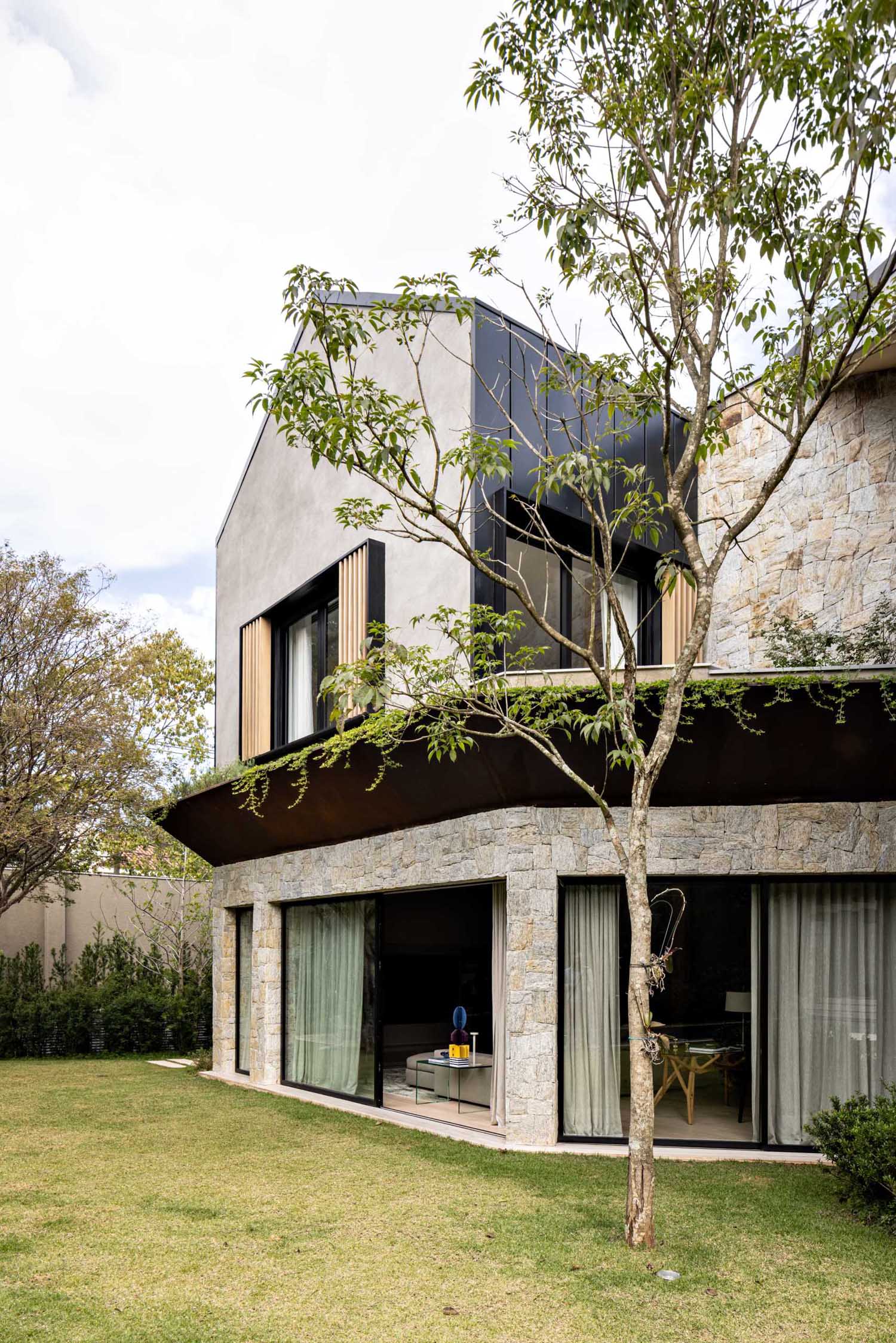 A modern home has a planter that wraps around its exterior, separating the main and upper floors.
