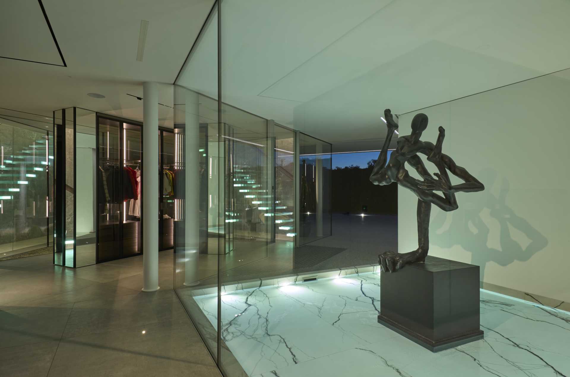 A modern house with glass walls showcases sculptures.