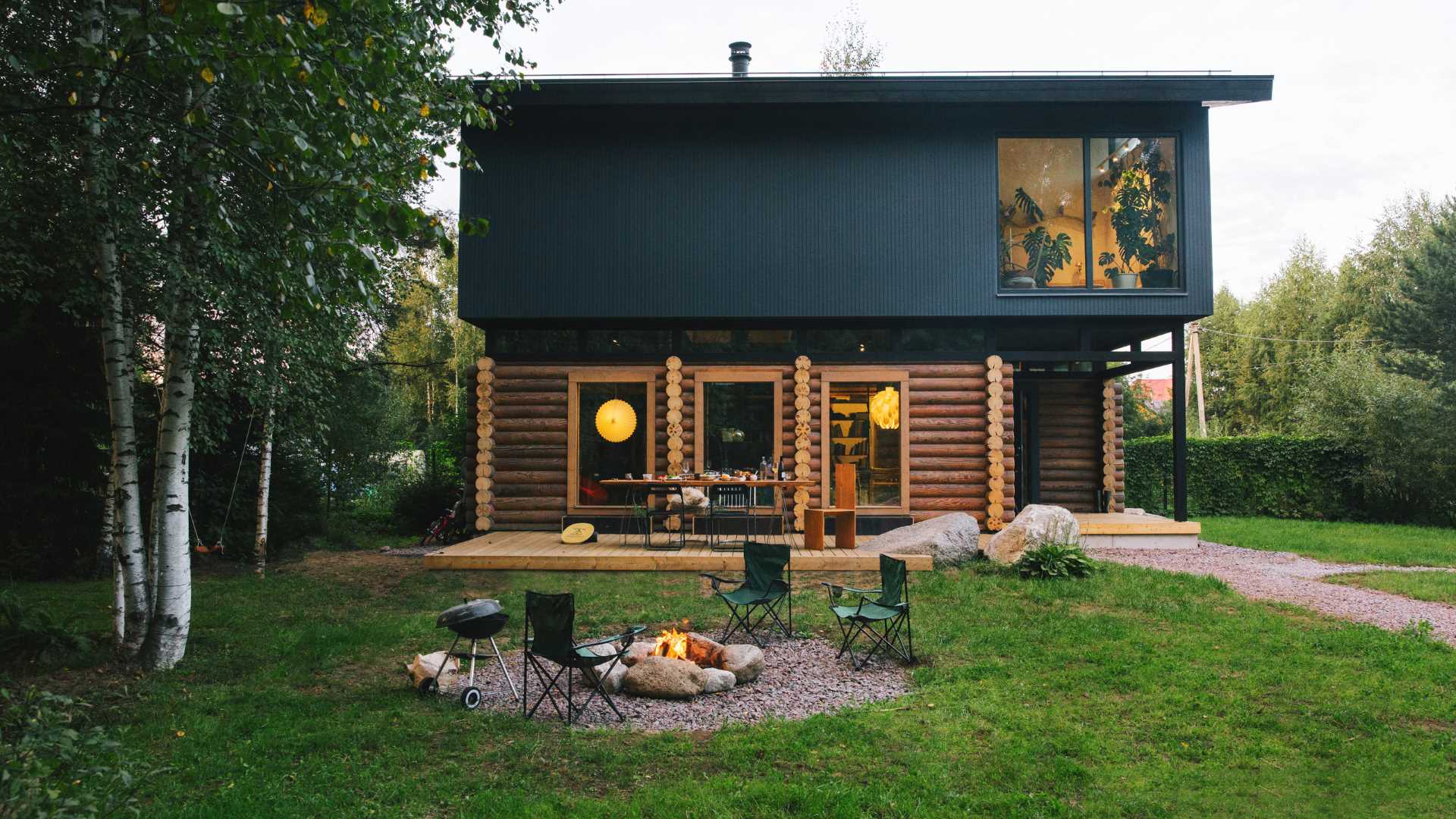 A log home topped with a modern black upper floor.