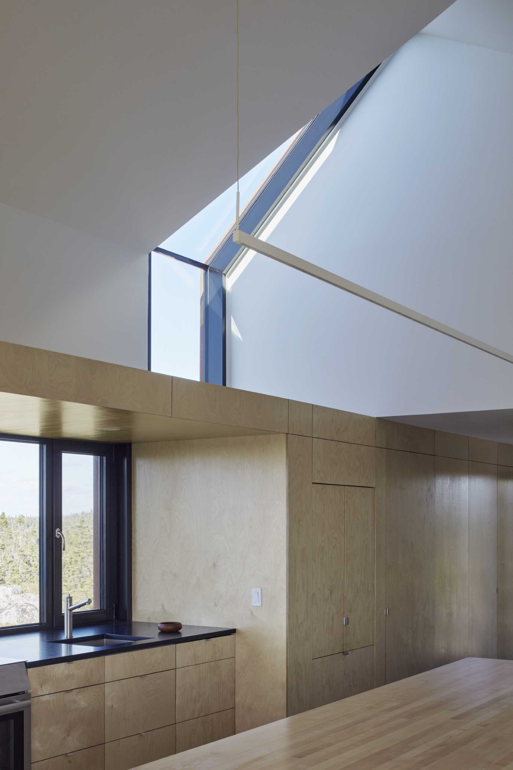 A modern house with a black-framed-window that transitions into a skylight.