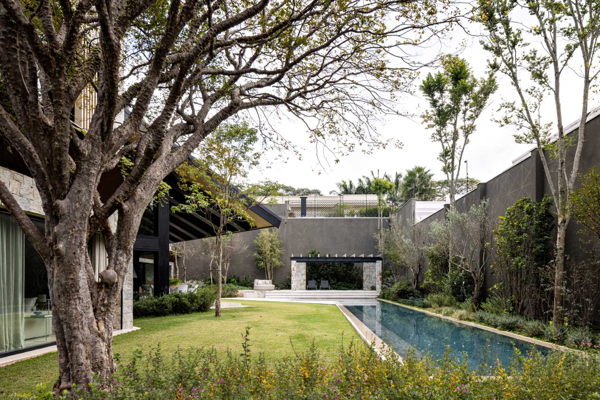 A modern house with a long swimming pool, yard, and cabana.