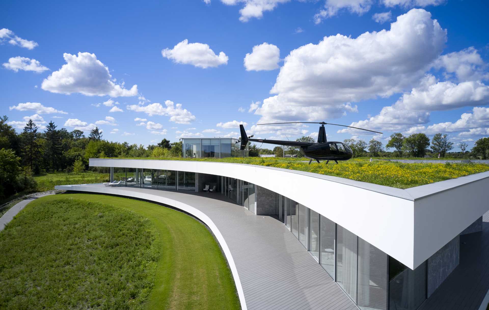 A modern house with a curved facade and an expansive green roof.