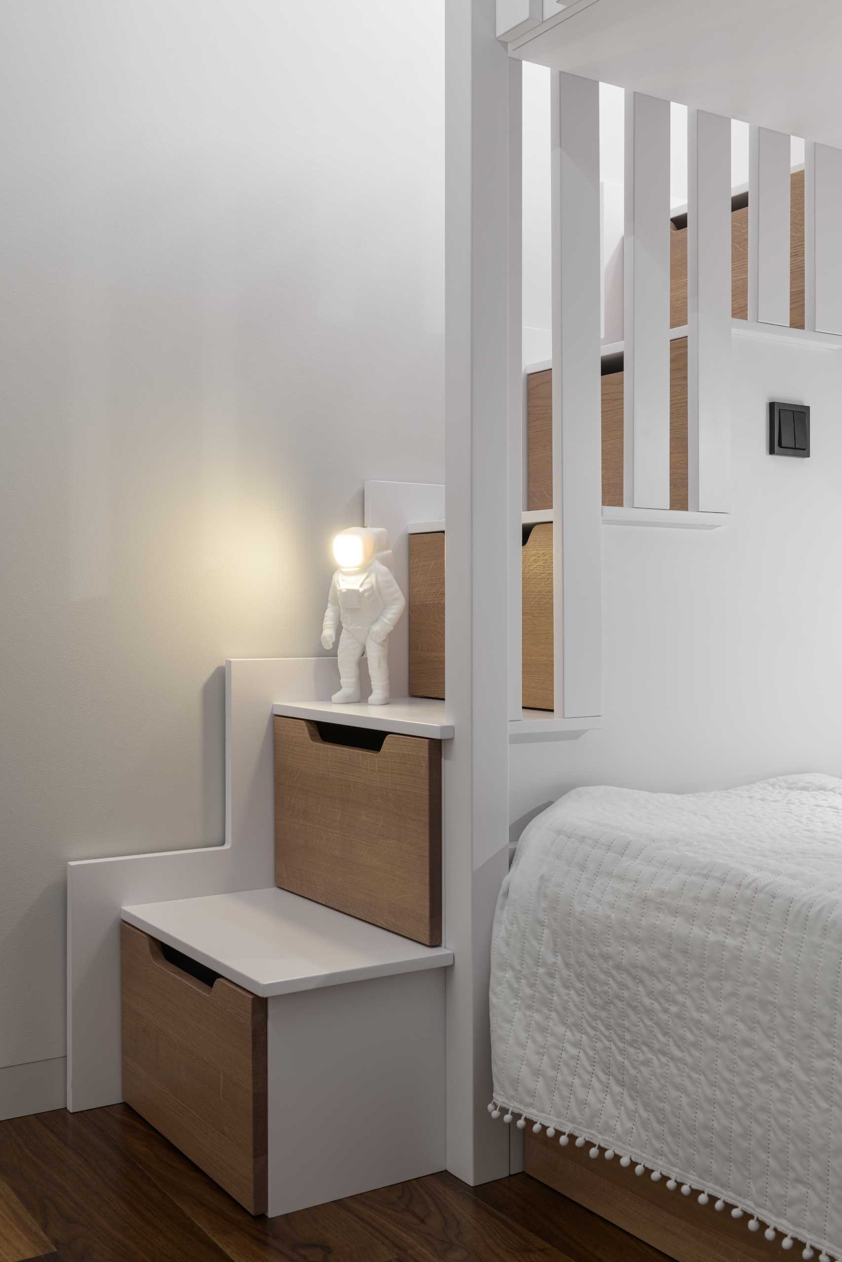 A modern kids bedroom with storage stairs that connect to a lofted play area.