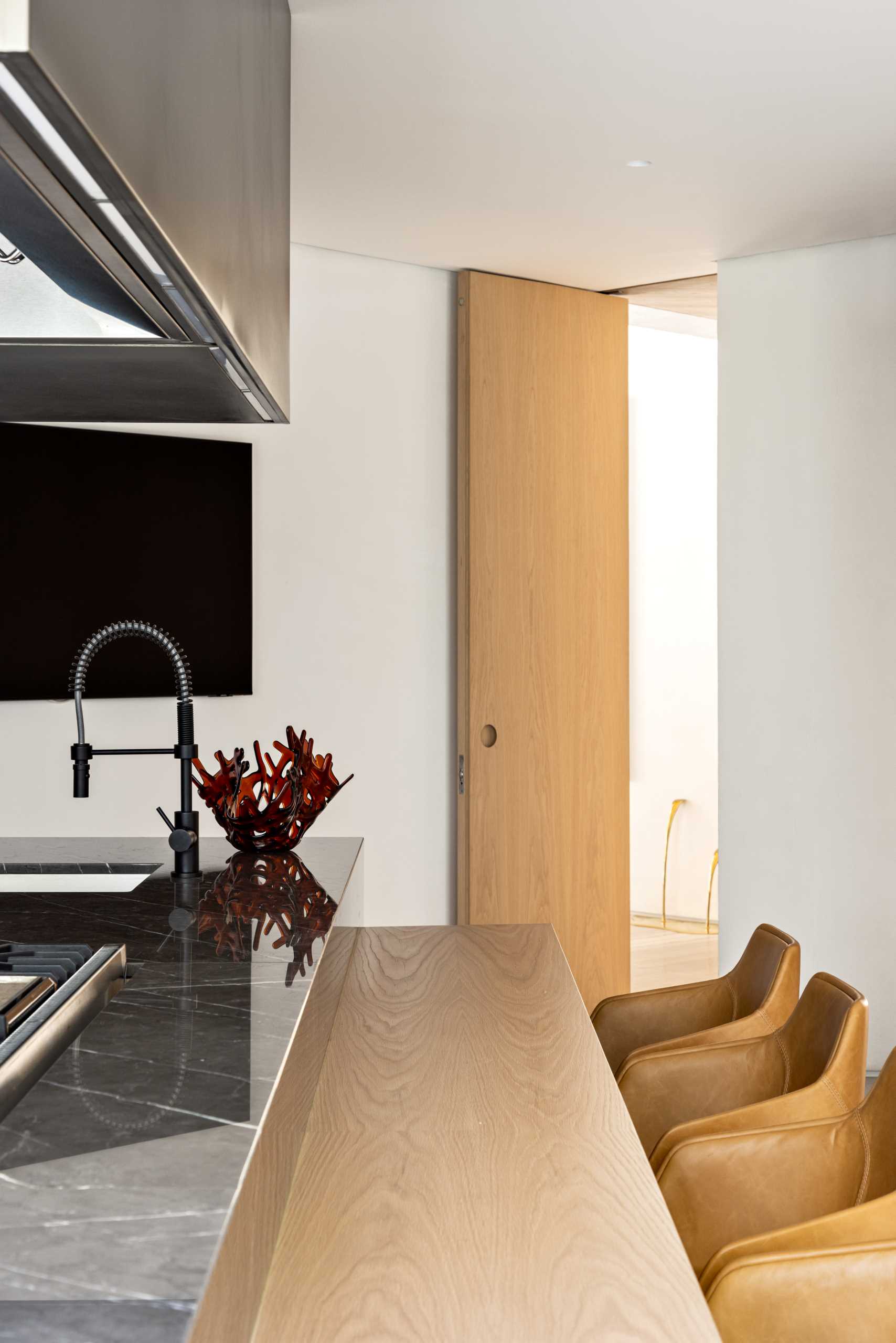 In this modern kitchen there's a large island with a lower wood countertop that people can sit at.