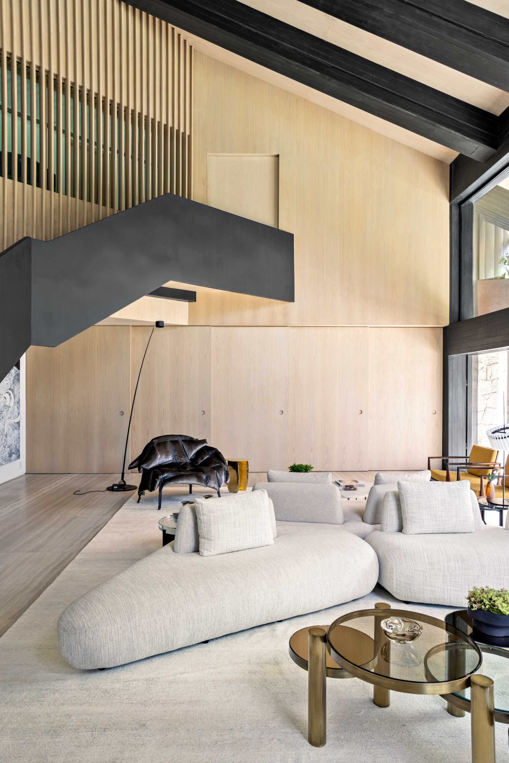 Behind this modern living room, there's a wood wall that slides open to reveal a casual dining area and a bar.