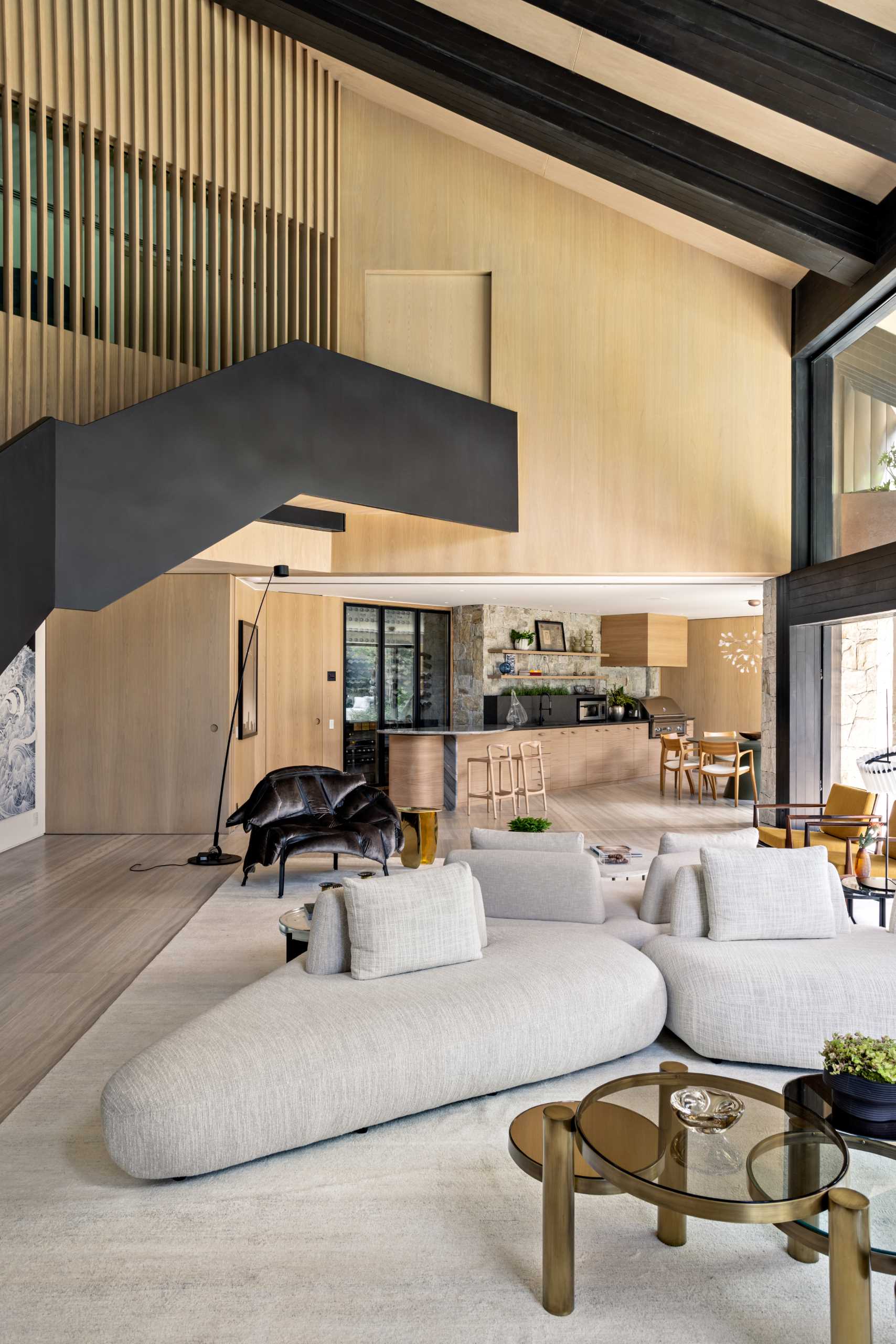 Behind this modern living room, there's a wood wall that slides open to reveal a casual dining area and a bar.