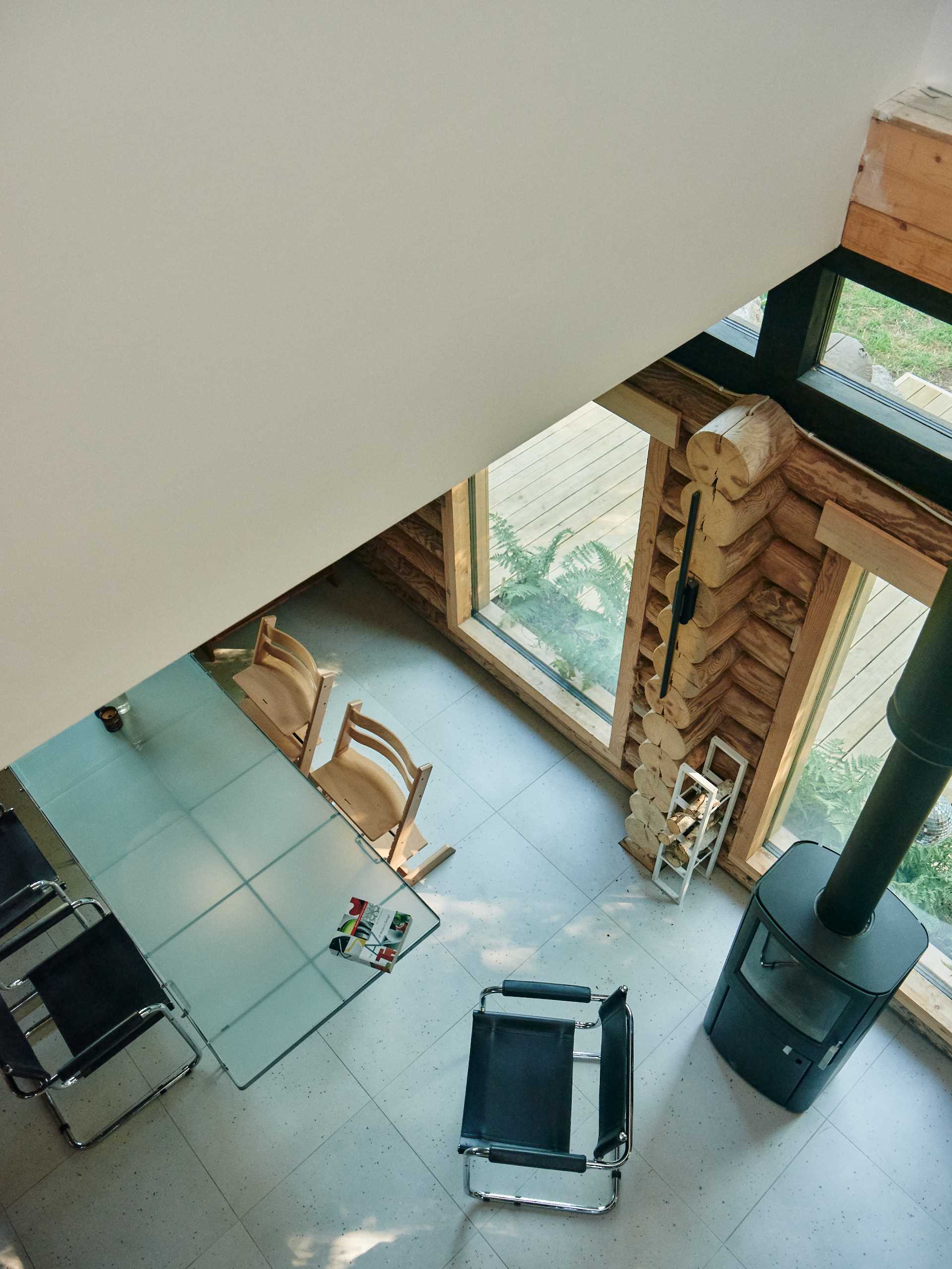 A modern log home with concrete floors and a glass dining table.