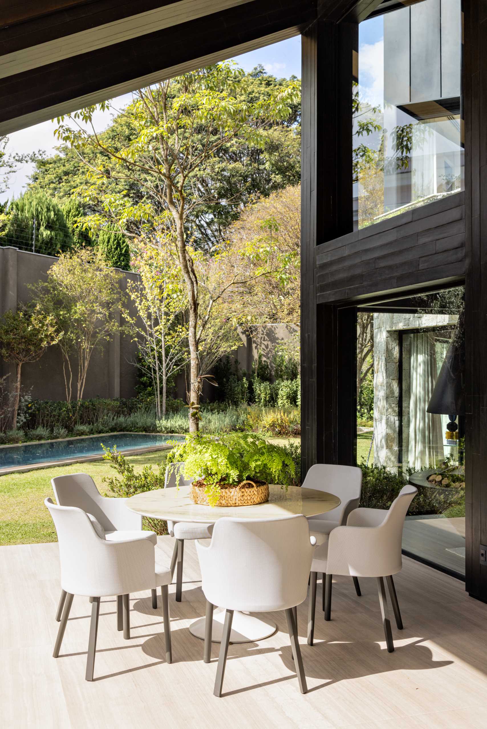 A modern house has a covered patio with lounge and dining areas.