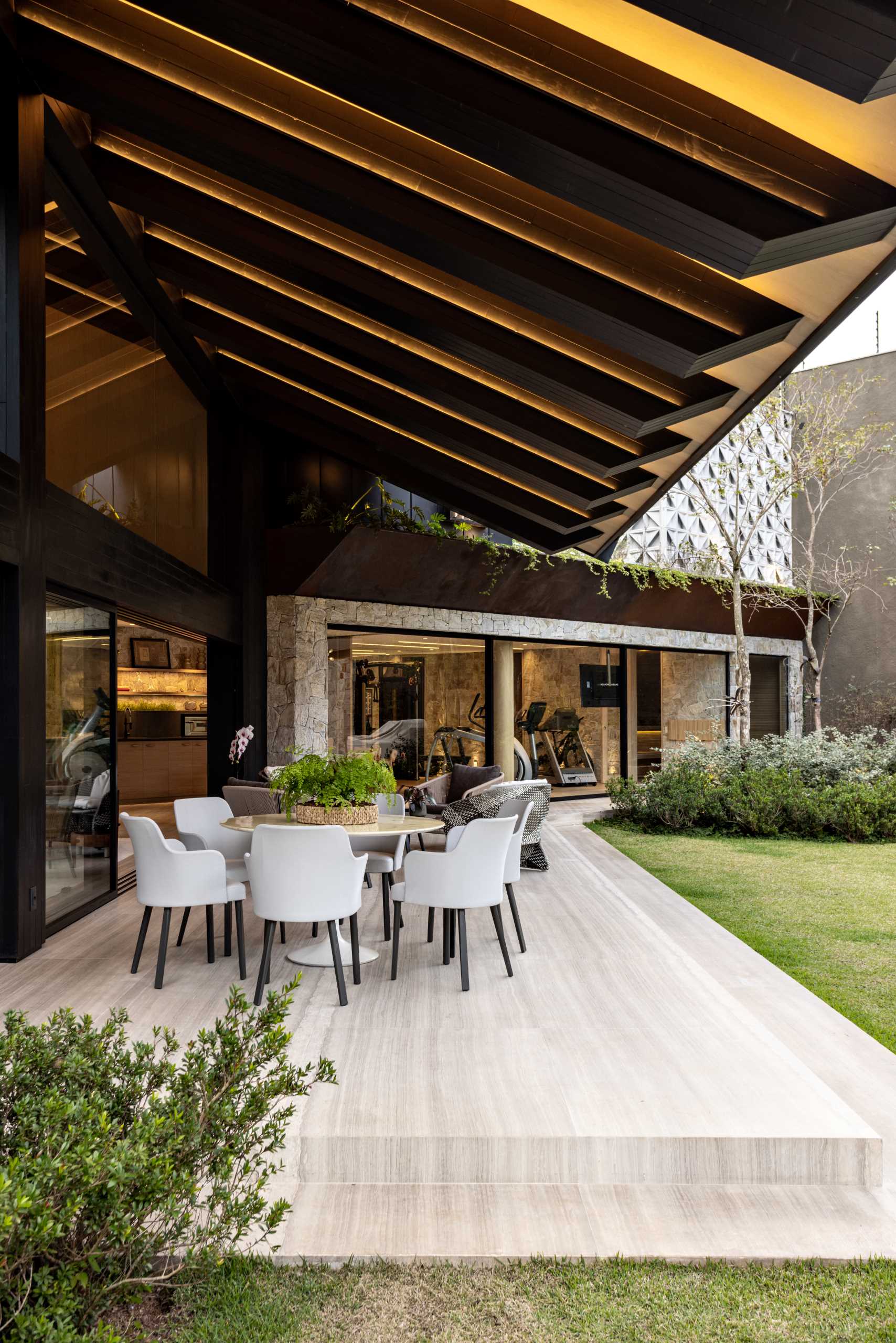 A modern house has a covered patio with lounge and dining areas.