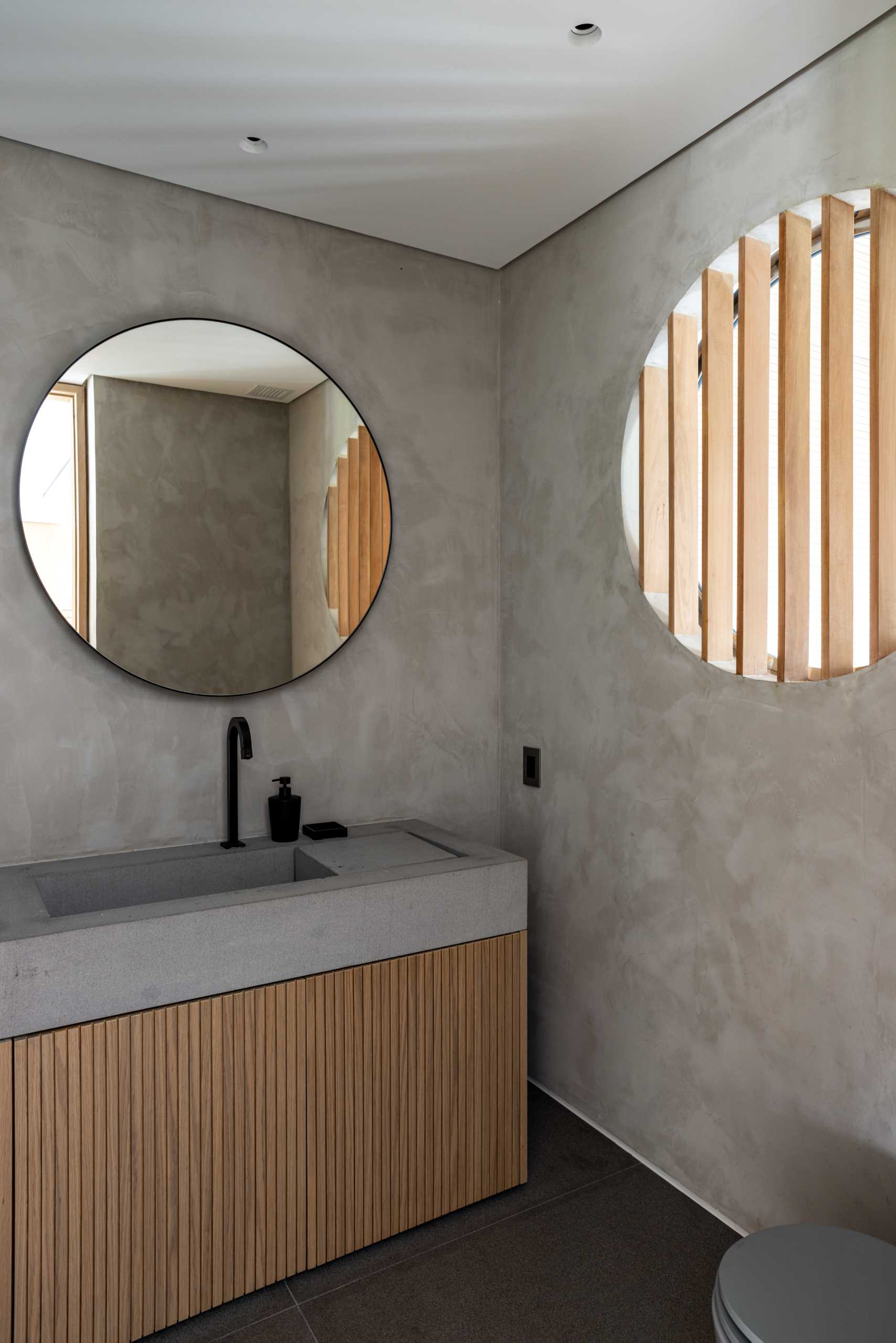 A small powder room with a round window that looks through to a sauna.