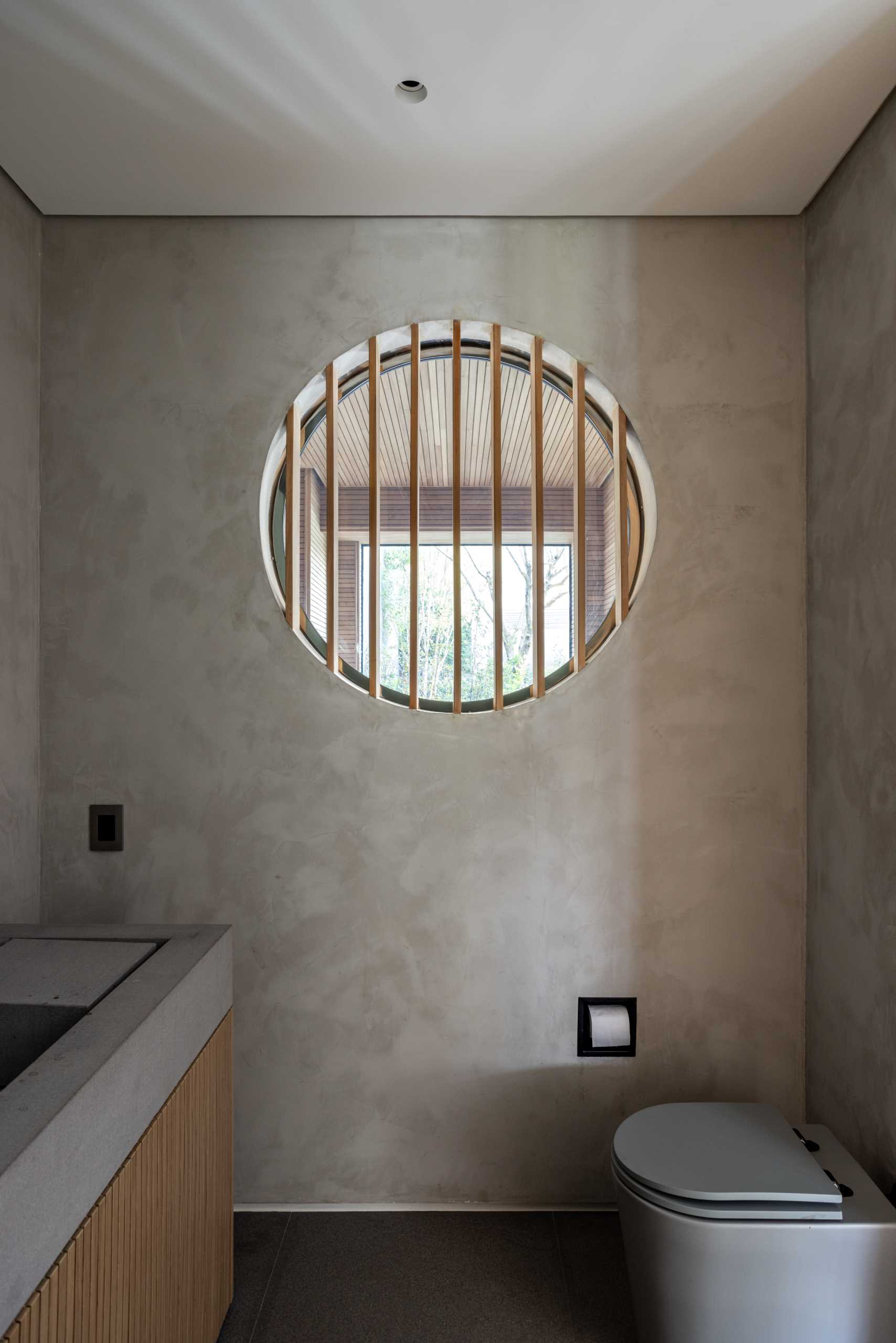 A small powder room with a round window that looks through to a sauna.