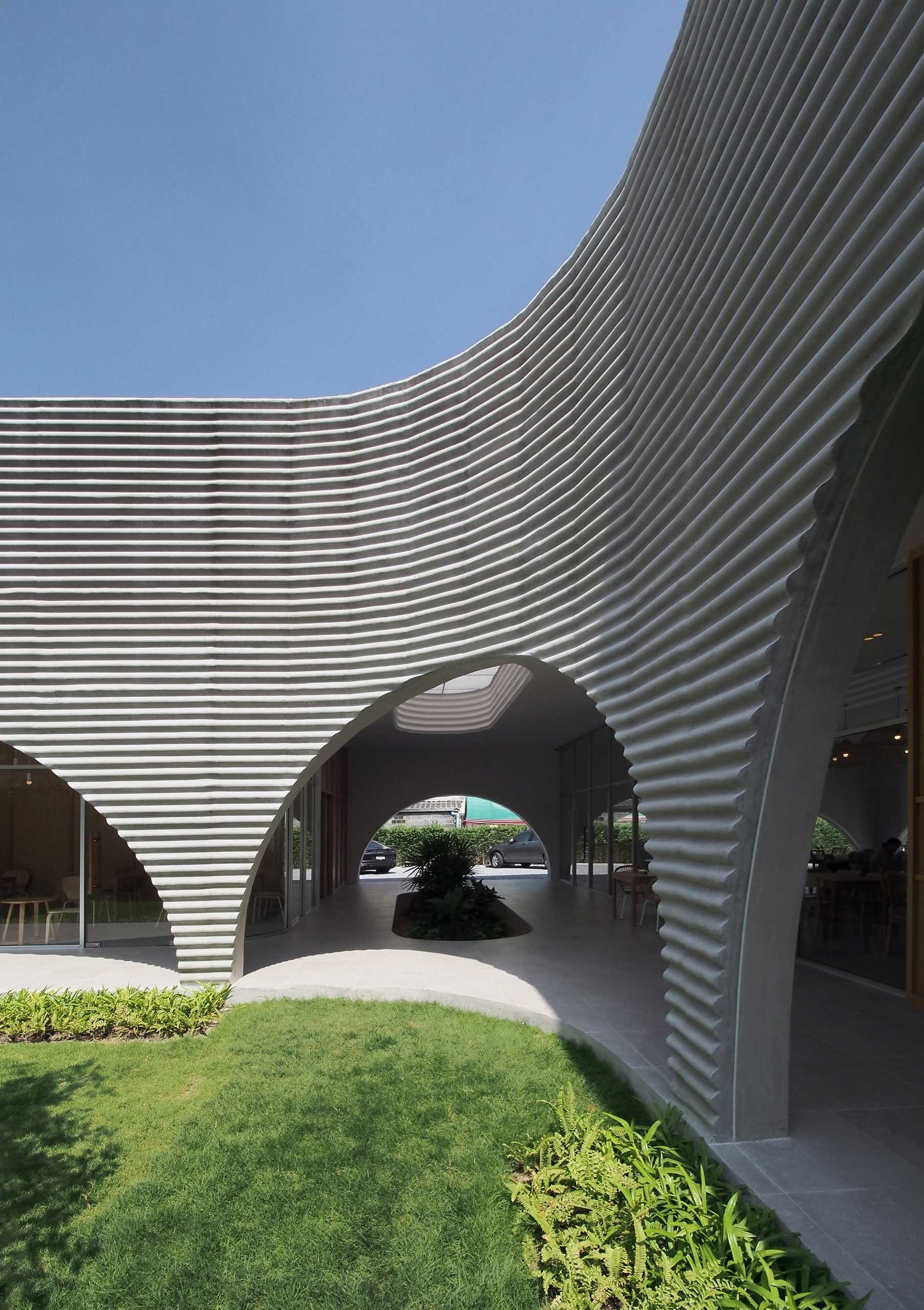 A modern restaurant and cafe with a wavy pre-case concrete facade and arched openings.