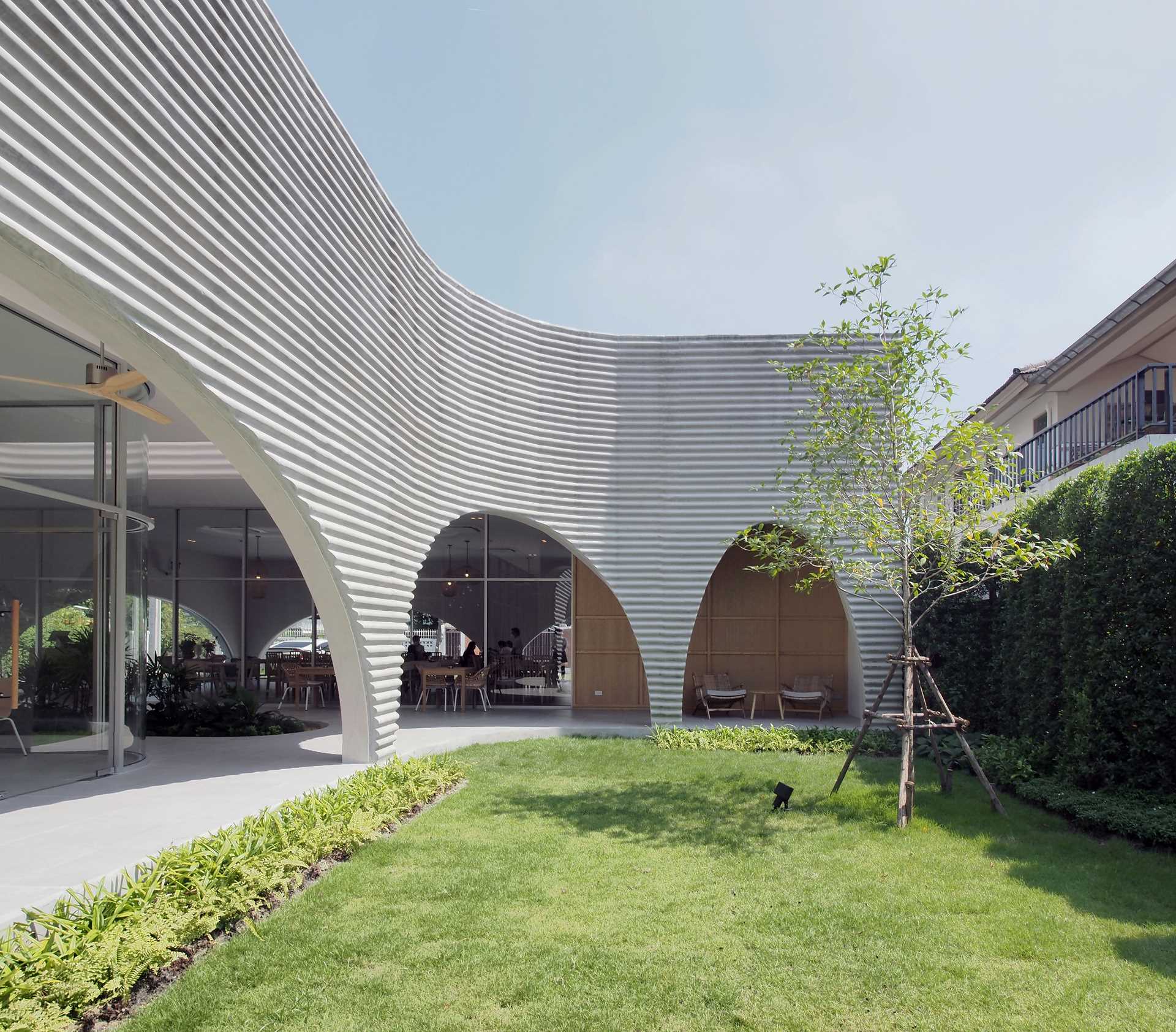 A modern restaurant and cafe with a wavy pre-case concrete facade and arched openings.