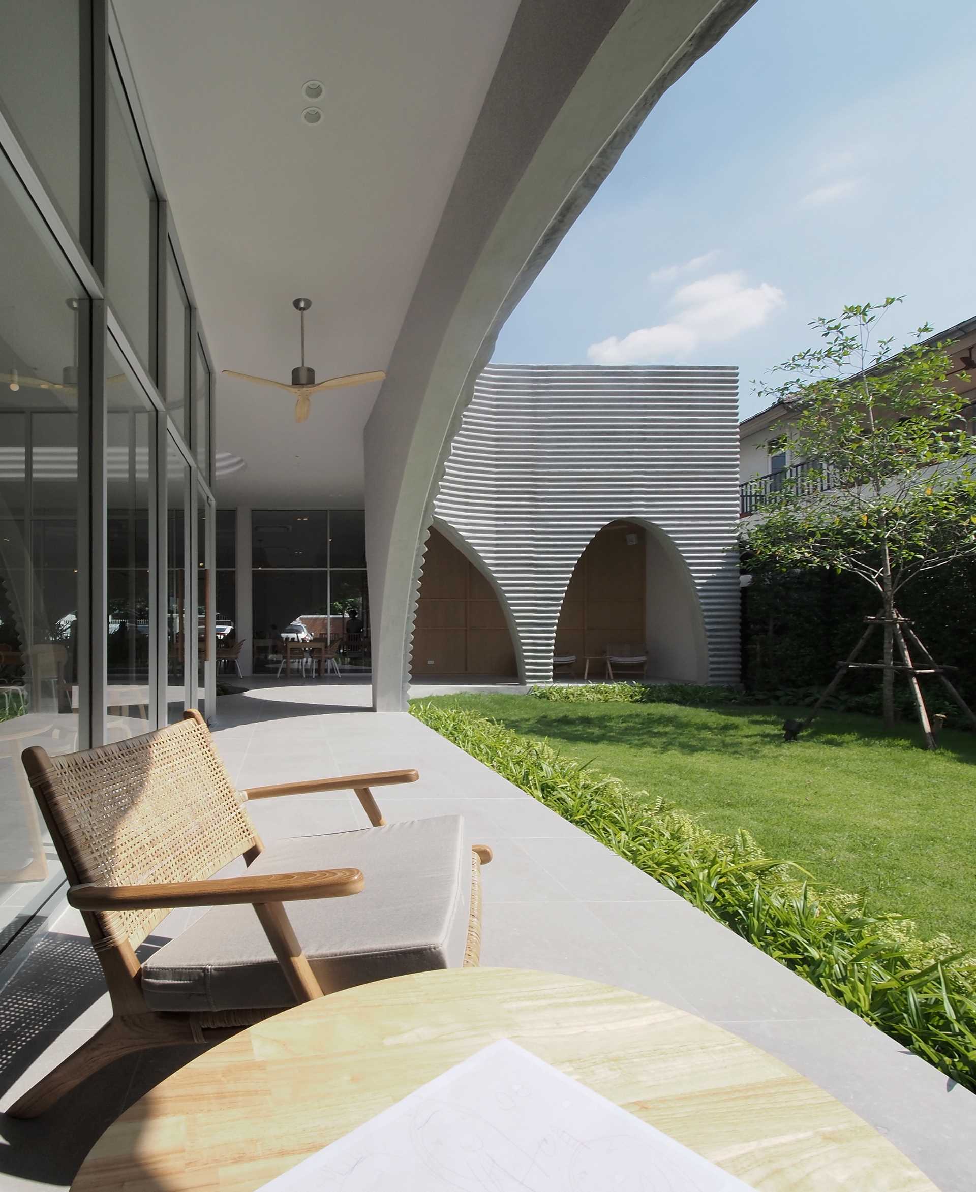 A modern cafe and restaurant with a covered patio and garden, and arched details.