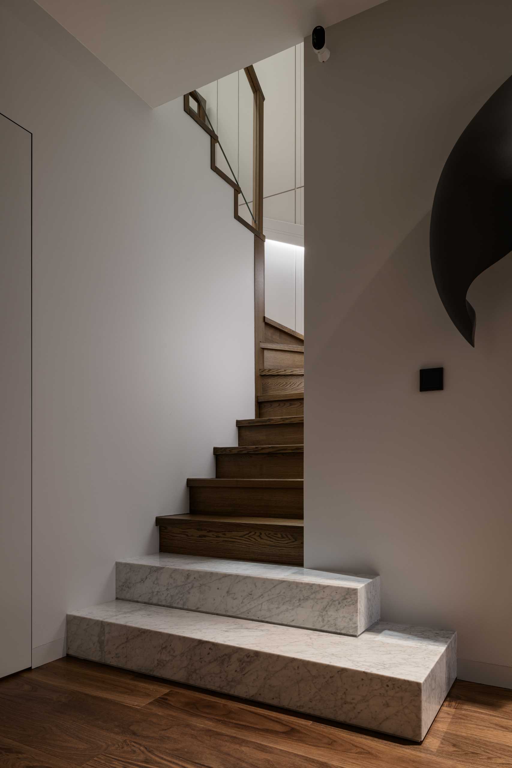 Modern wood and stone stairs with handrails that have hidden lighting.