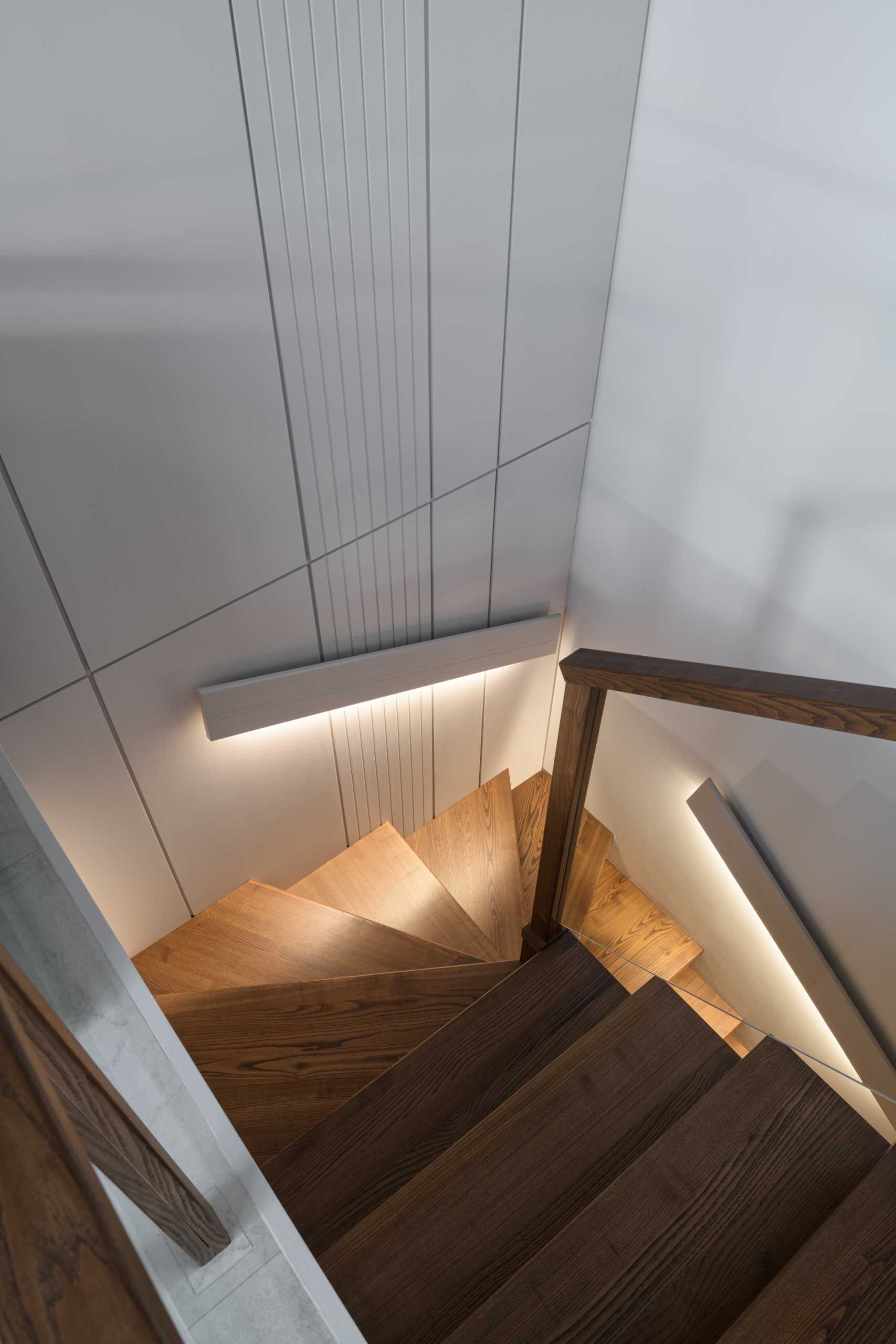 Modern wood stairs with handrails that have hidden lighting.