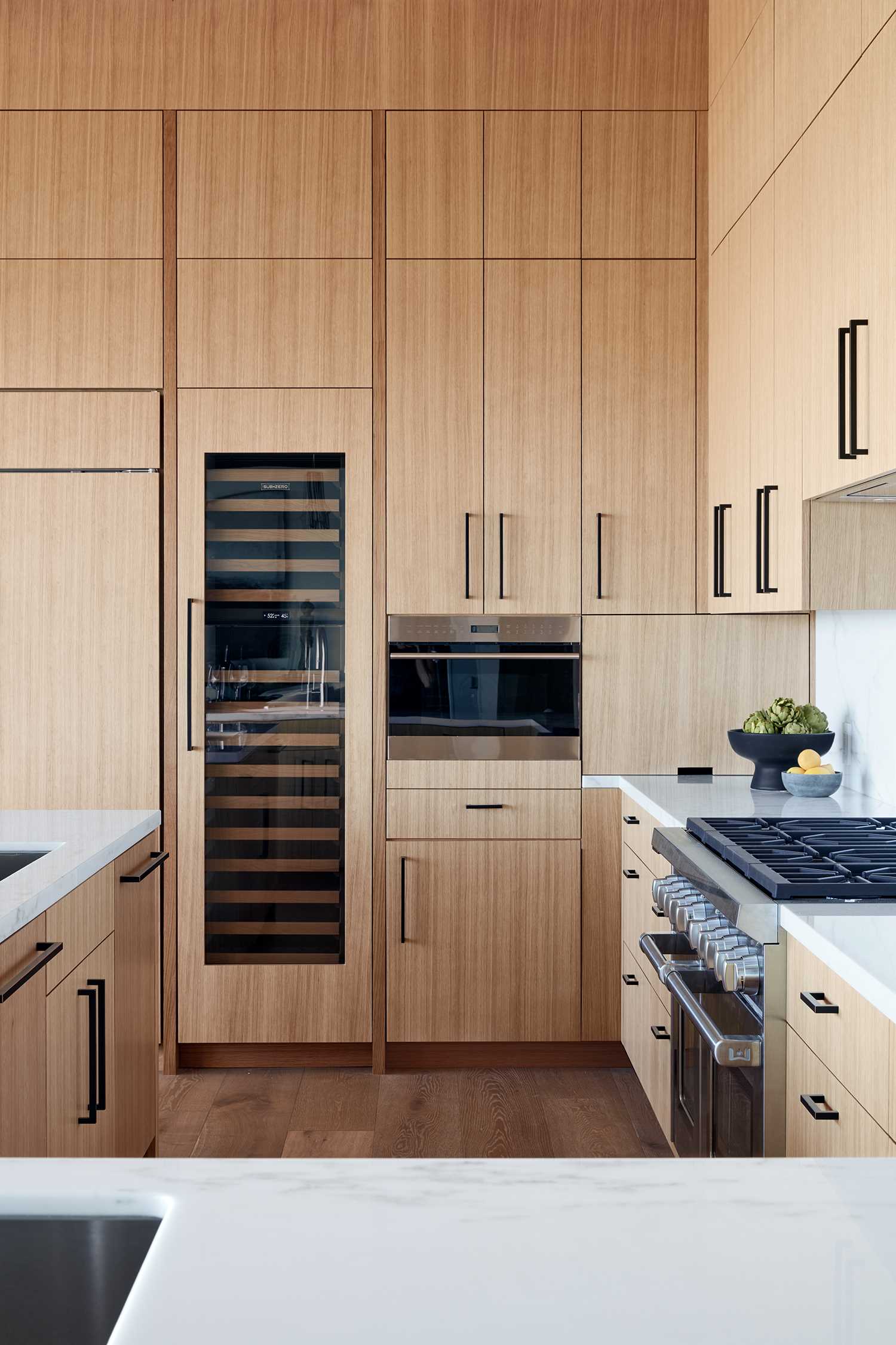 A modern wood kitchen with white countertops.
