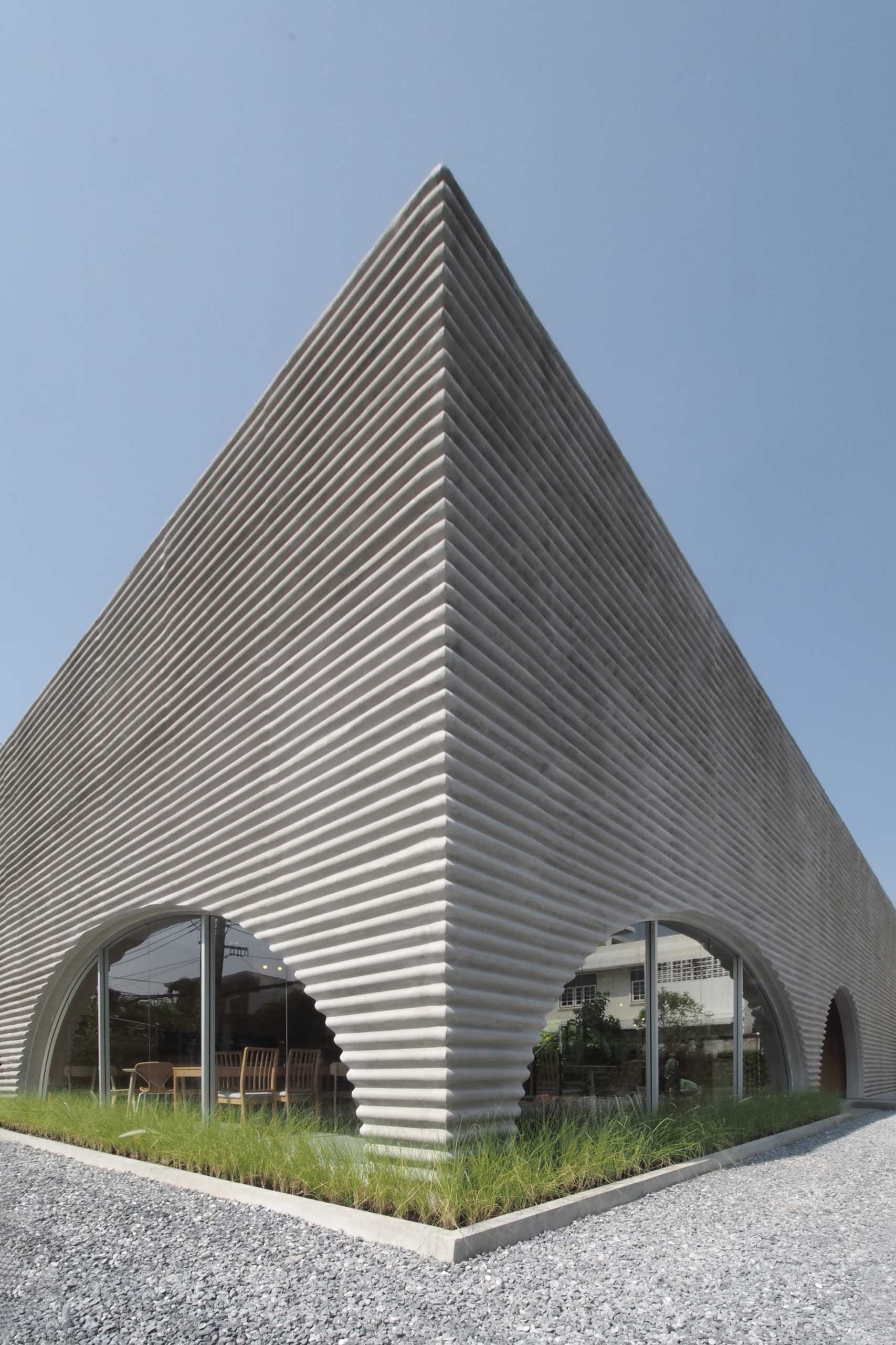 A modern restaurant and cafe with a wavy pre-case concrete facade and arched openings.