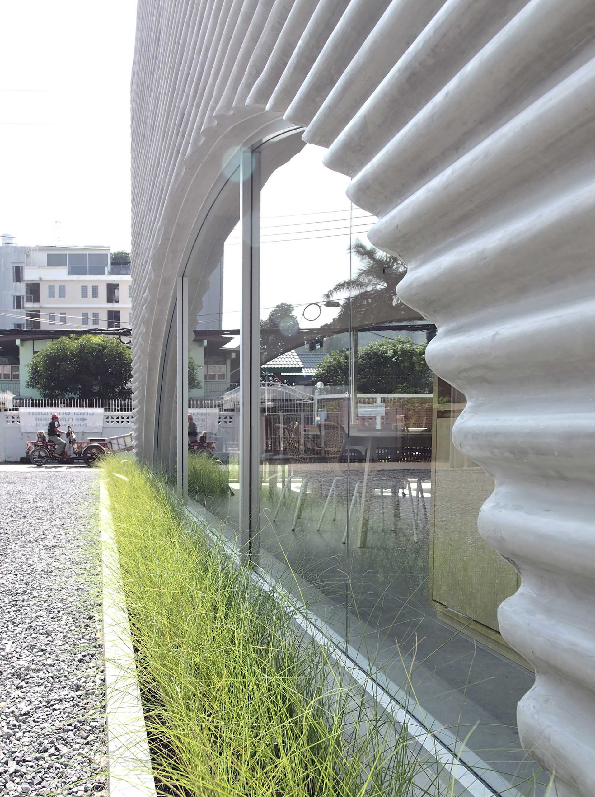 A modern restaurant and cafe with a wavy pre-case concrete facade and arched openings.