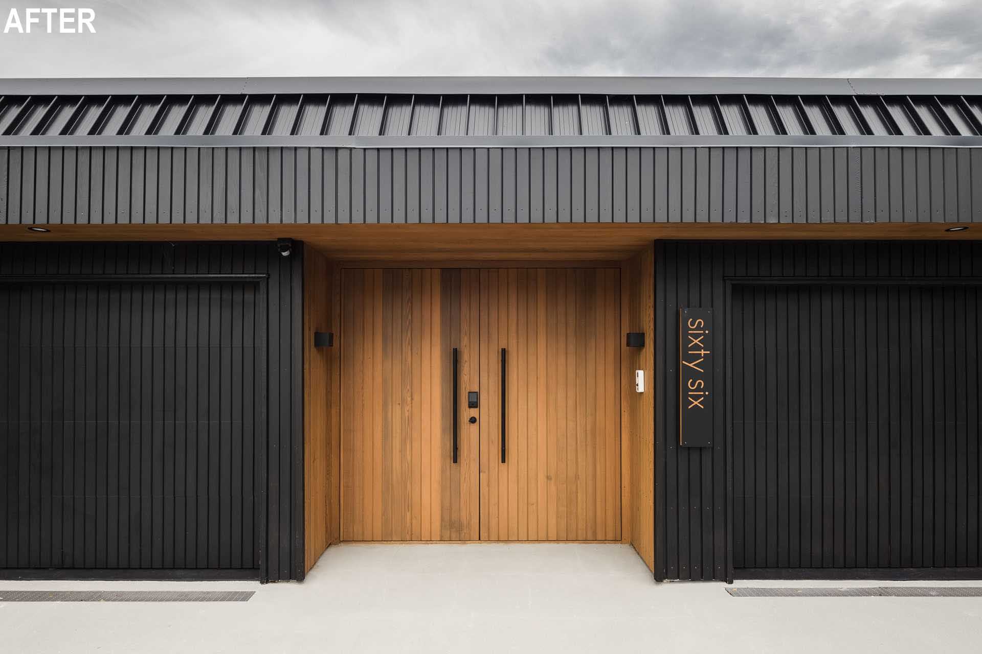 Welcoming guests to this modern home are wood front doors that contrast the vertical black exterior.