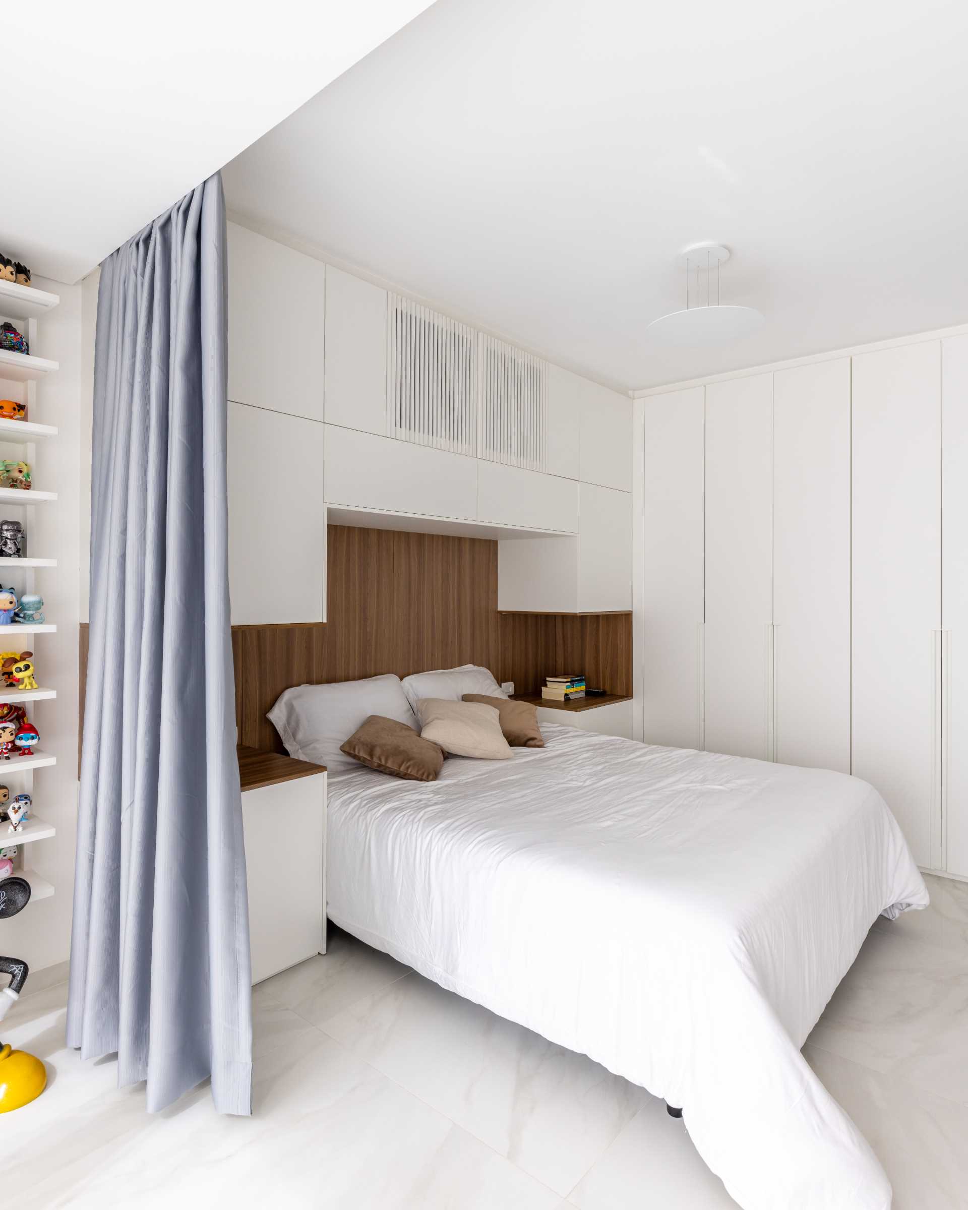 A modern open-plan bedroom with curtains for walls, storage, and wood headboard.