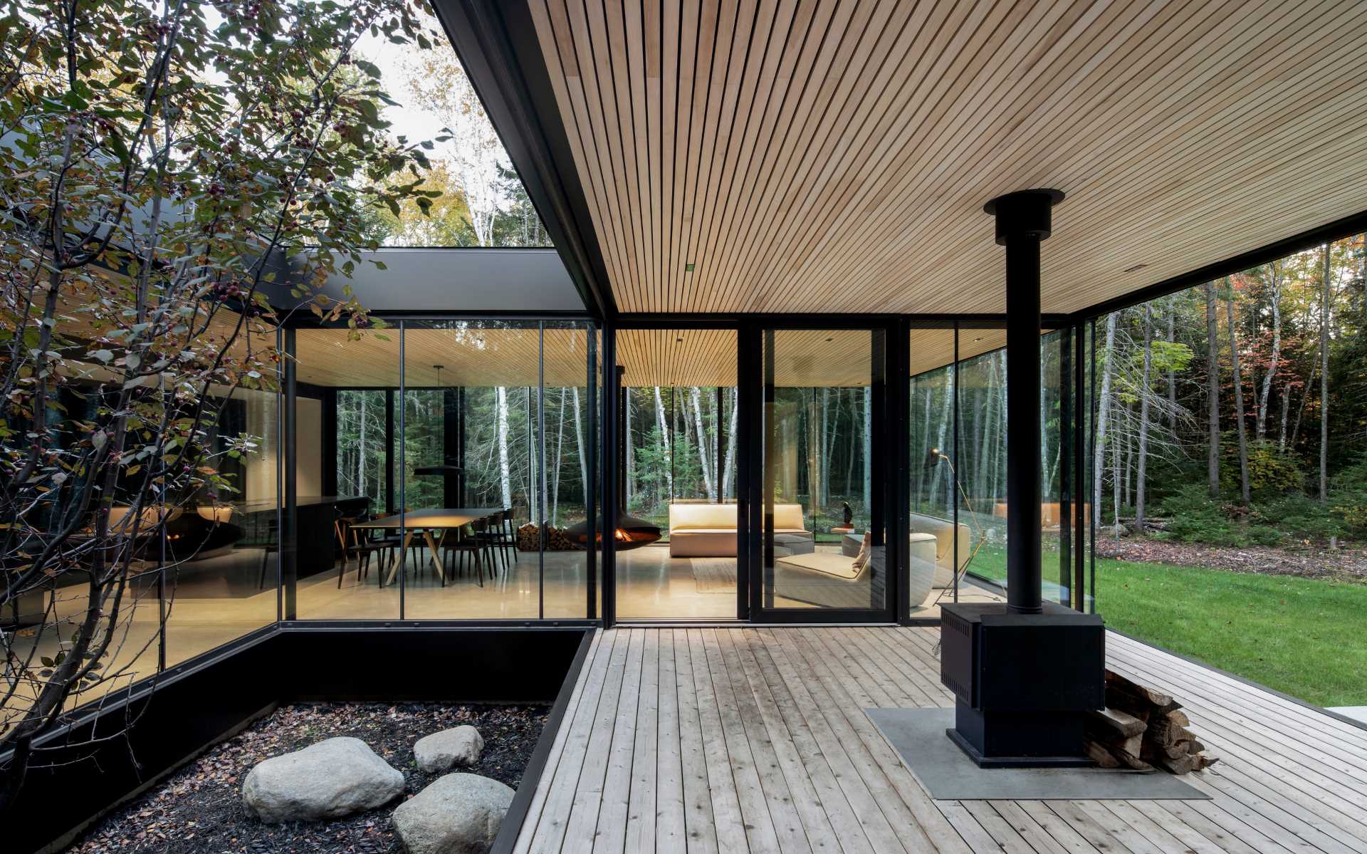 A modern house with a covered outdoor area and floor-to-ceiling windows.