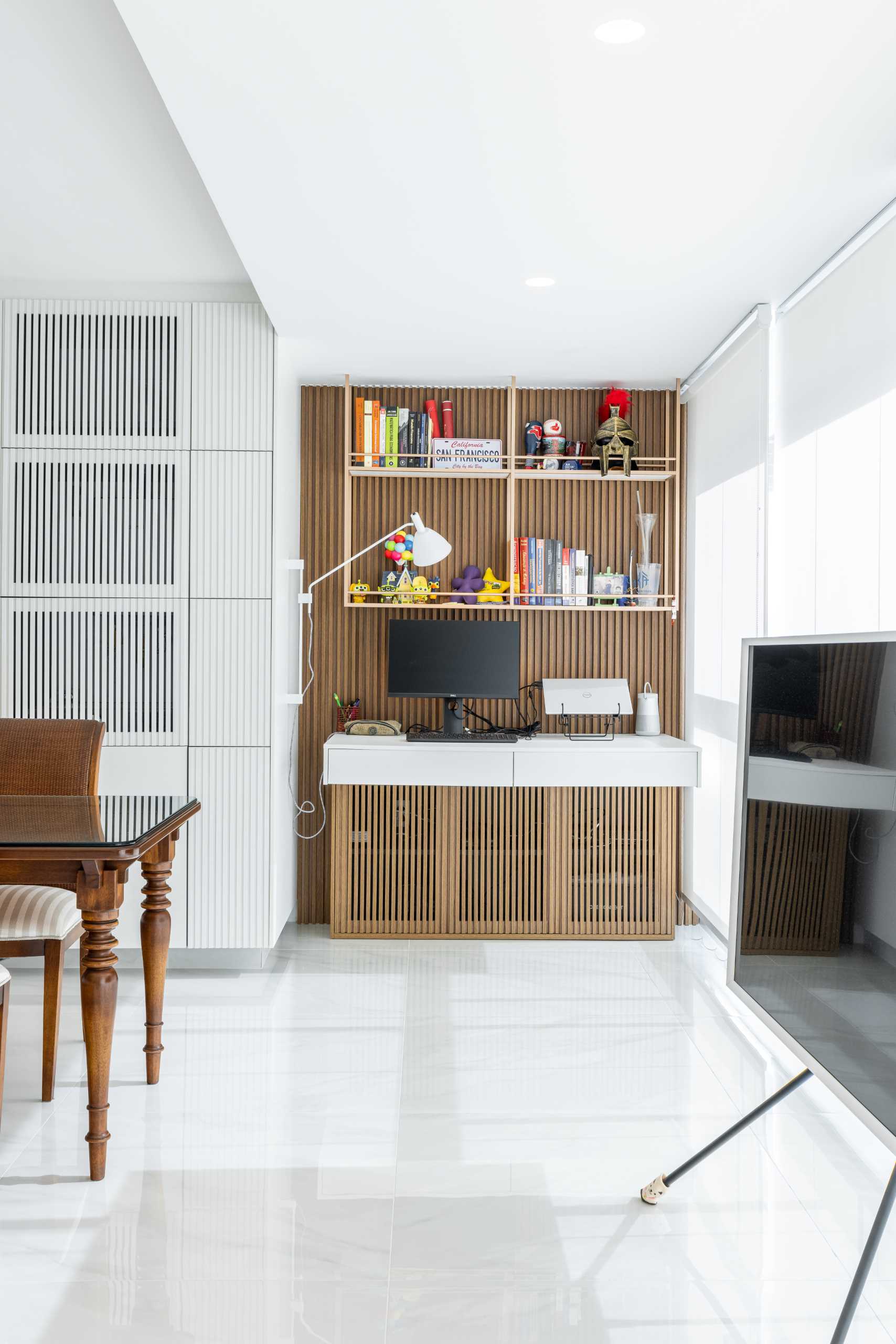 A wood accent wall is featured by the windows and acts as a backdrop for the desk.