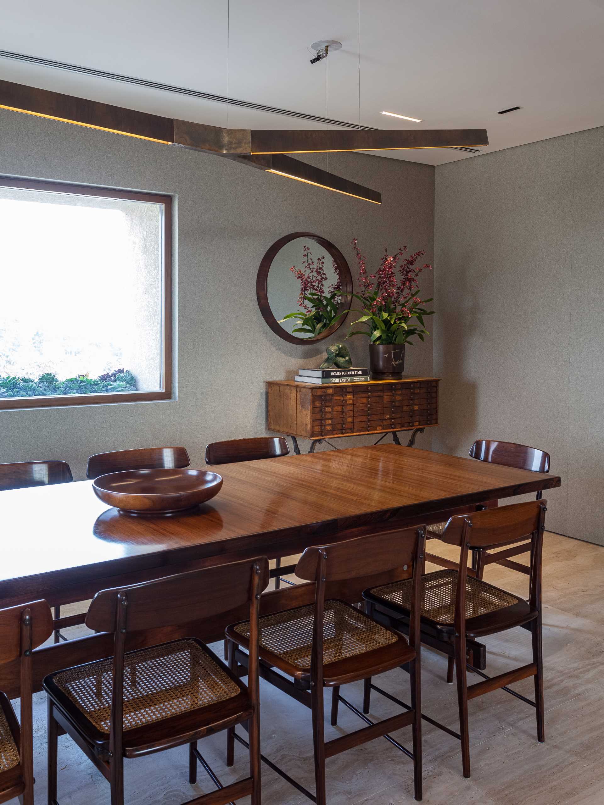 The dining room includes a large wood table and surrounding chairs designed by Sergio Rodrigues, while the floor is Roman Travertine Marble.