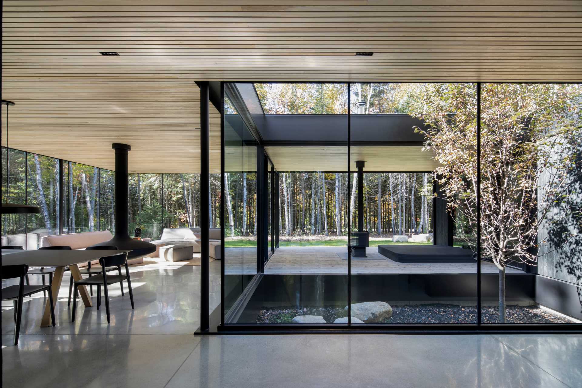 The entryway of this modern home provides glimpses of the interior, while concrete floors have been paired with a wood ceiling for a modern appearance.