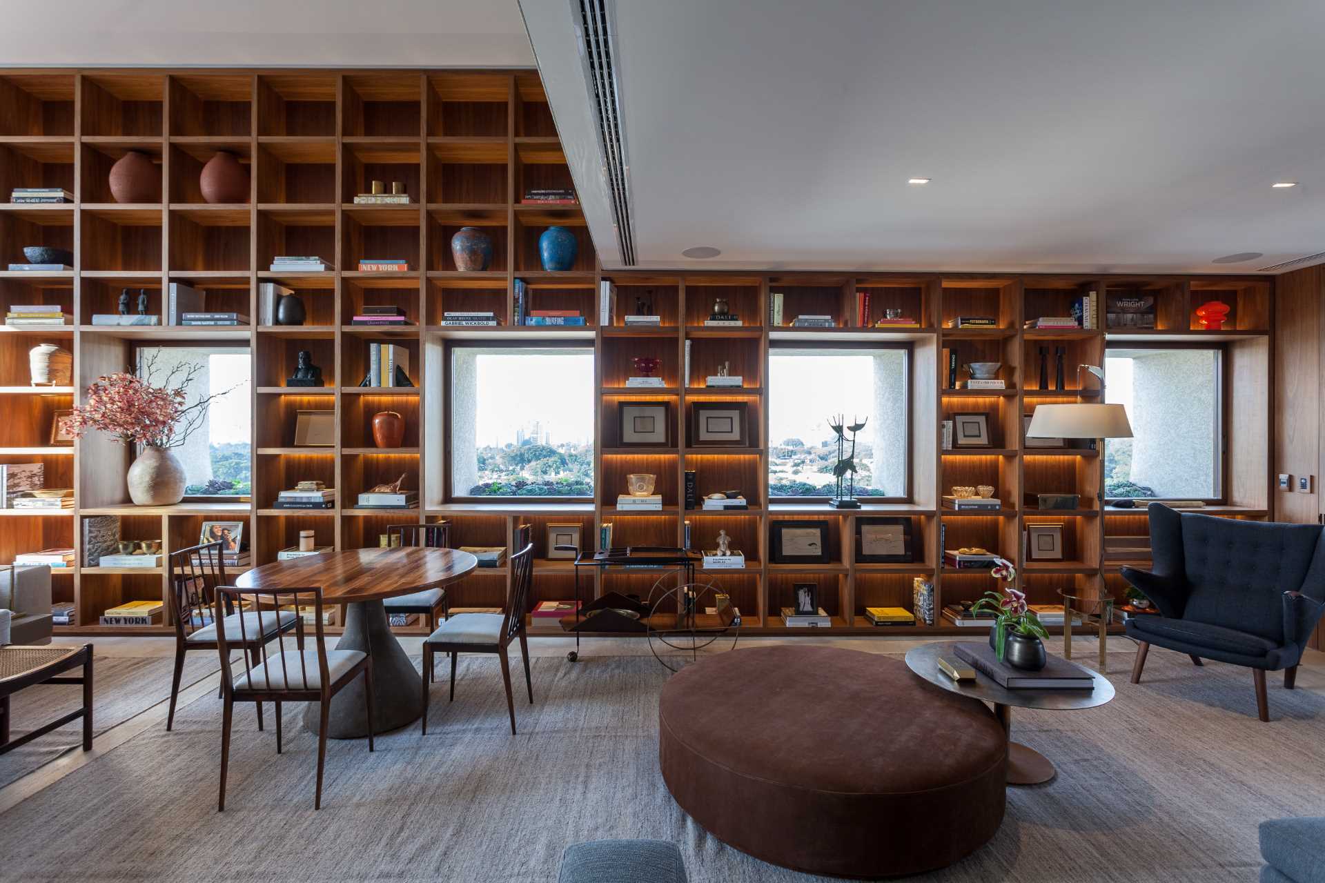 The design of this bookshelf allows the focus to be on the multiple windows that also share the wall, with the shelves framing the windows as if they were paintings.
