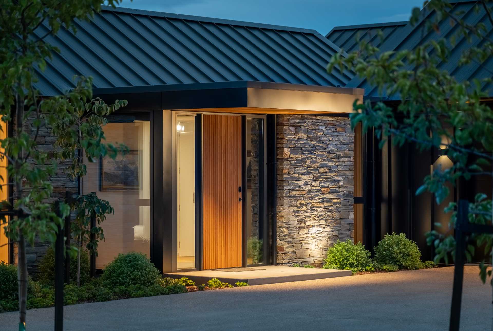 The front door of a modern house also has a stone accent wall.