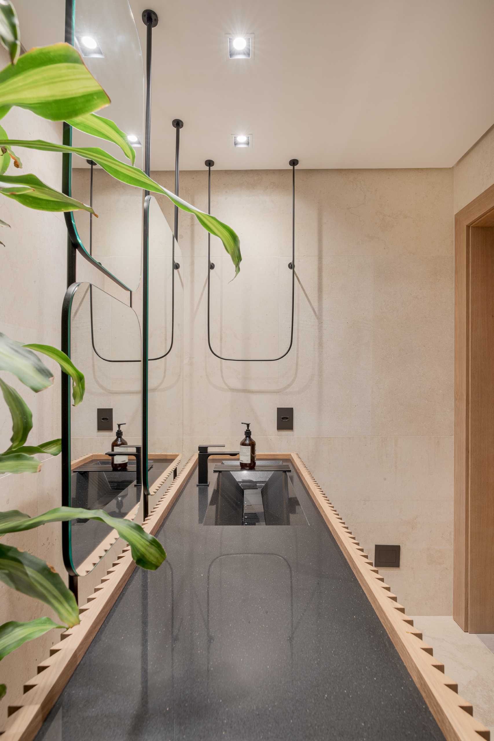 A modern powder room includes a wood vanity and a black countertop with built-in sink.