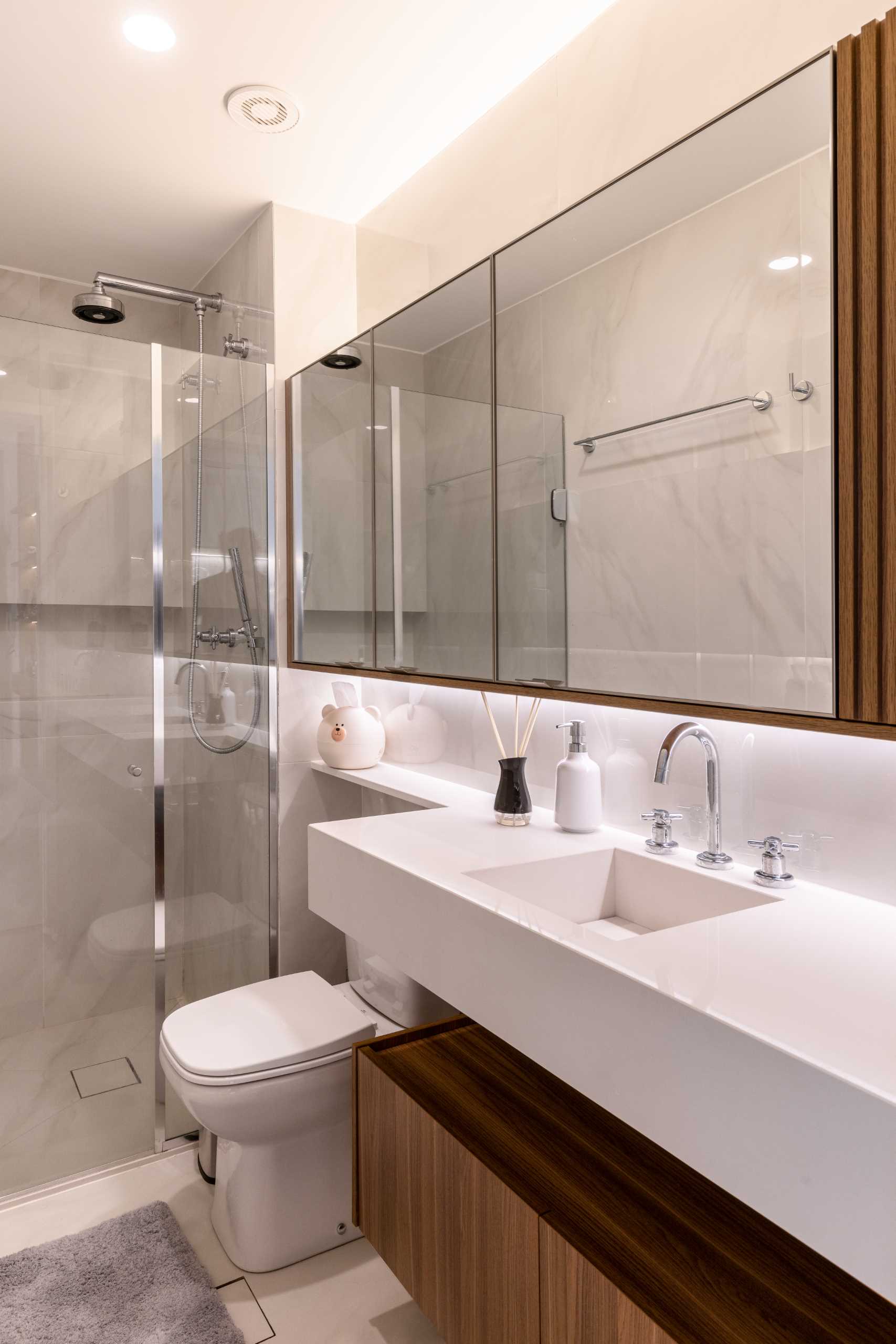 در حمام، یک کابینت چوبی پایین‌تر، یک روشویی با سینک توکار، و یک دوش روشویی وجود دارد.