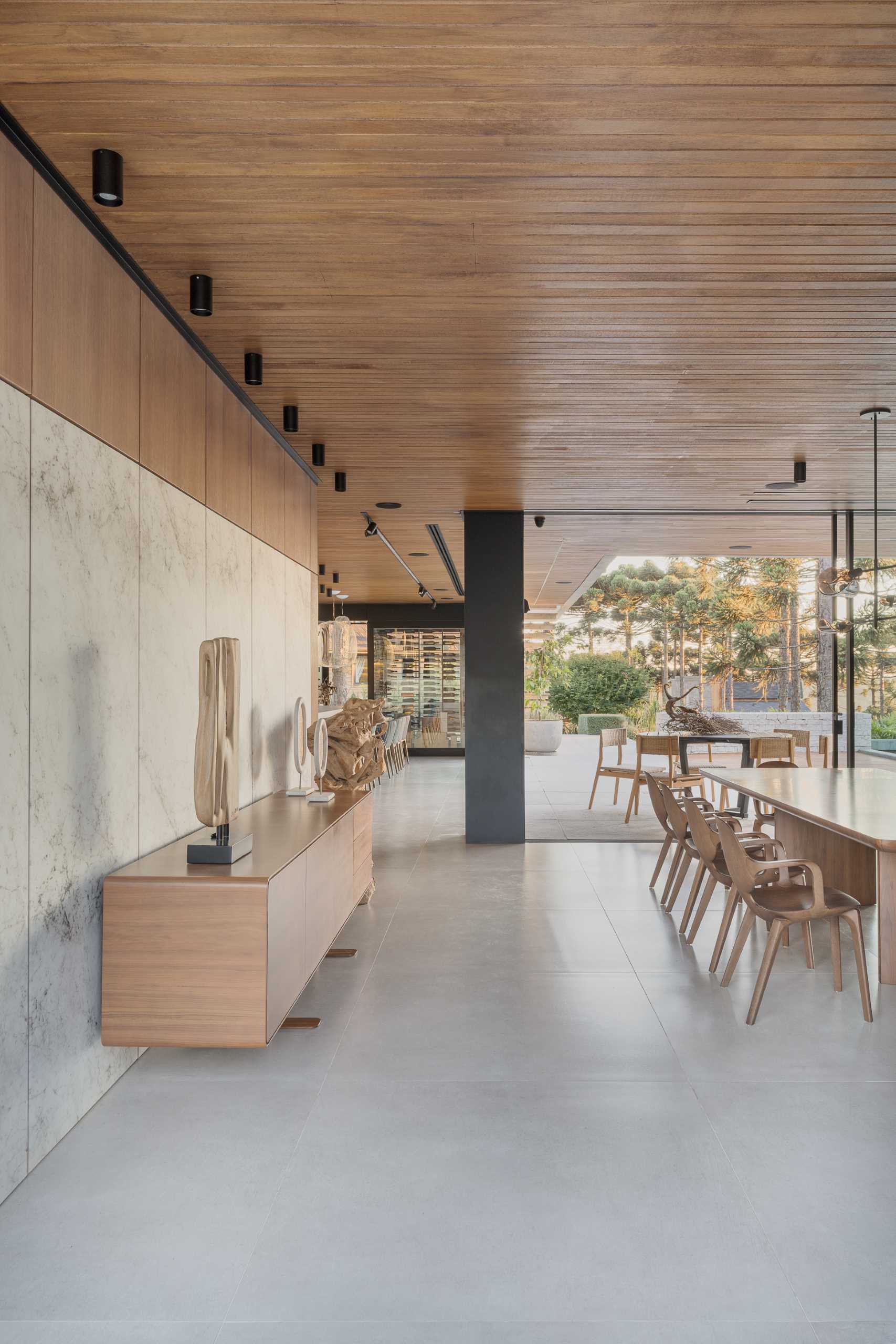 A built-in cabinet with glass doors stores complements this modern dining area, while the wall features stone panels and a wood sideboard.