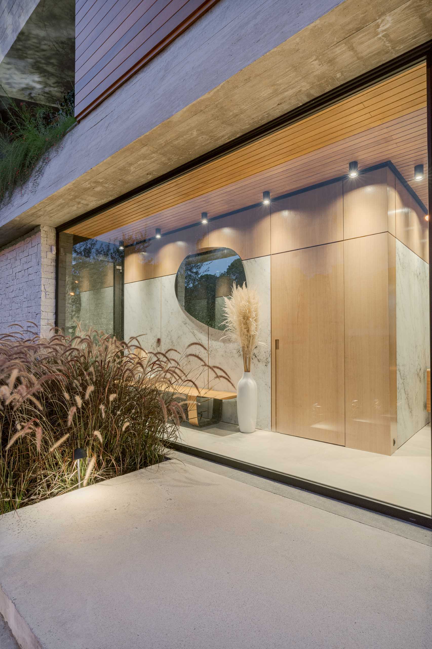 A modern entryway with floor-to-ceiling windows and a bench, provides access to a powder room.