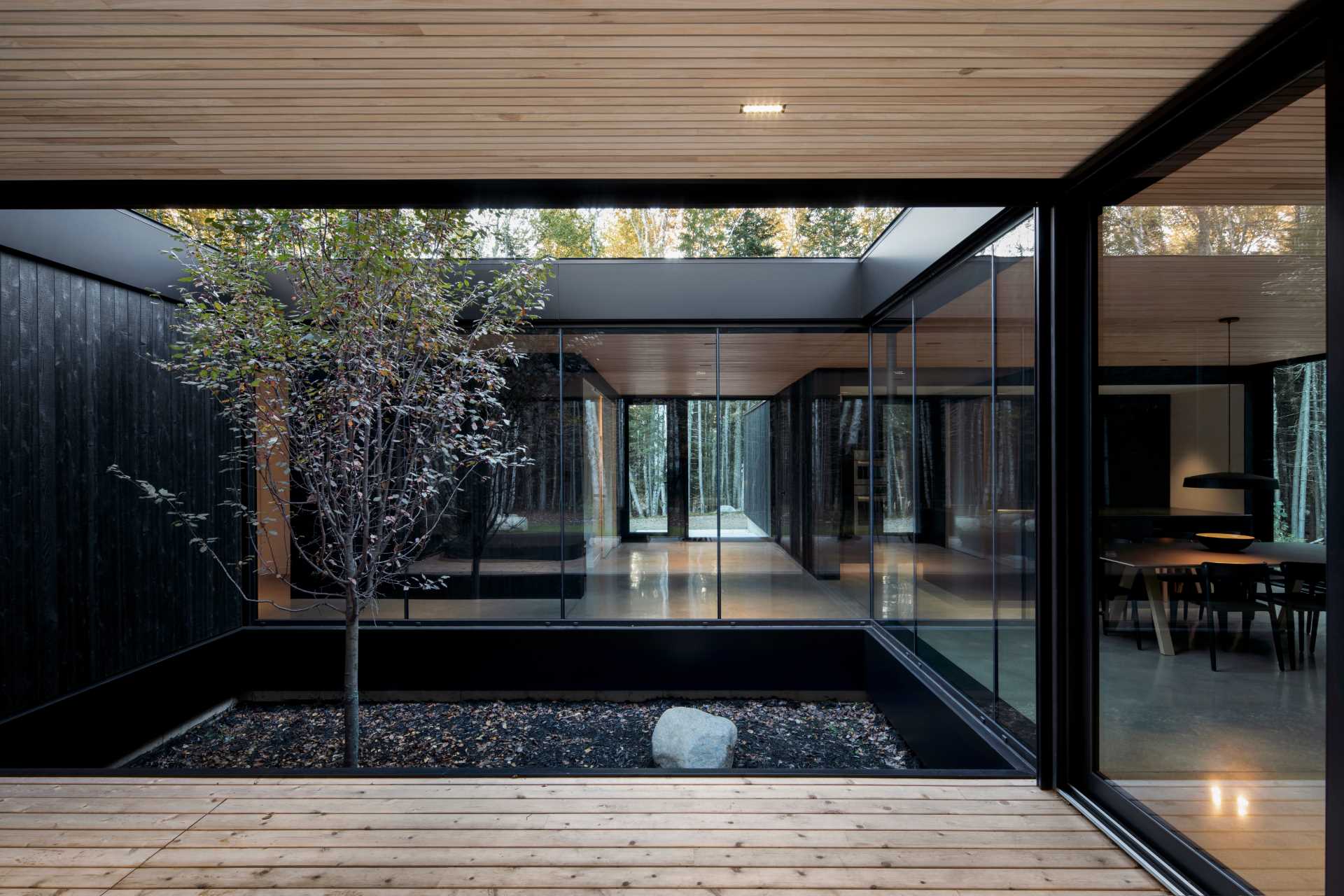 A modern house with a covered outdoor area and floor-to-ceiling windows.