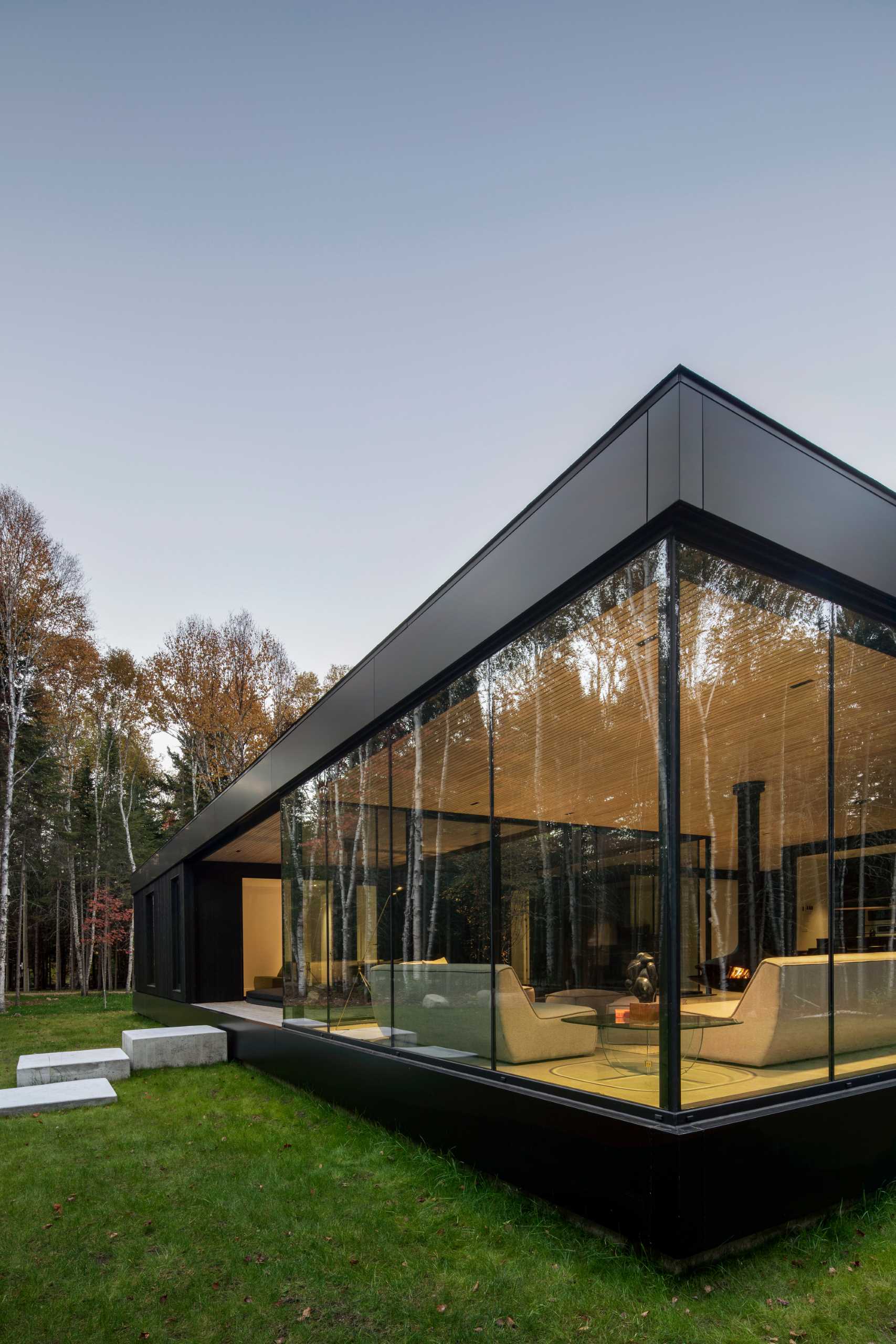 The striking black metal and wood exterior of this modern home contrasts the bright interior.