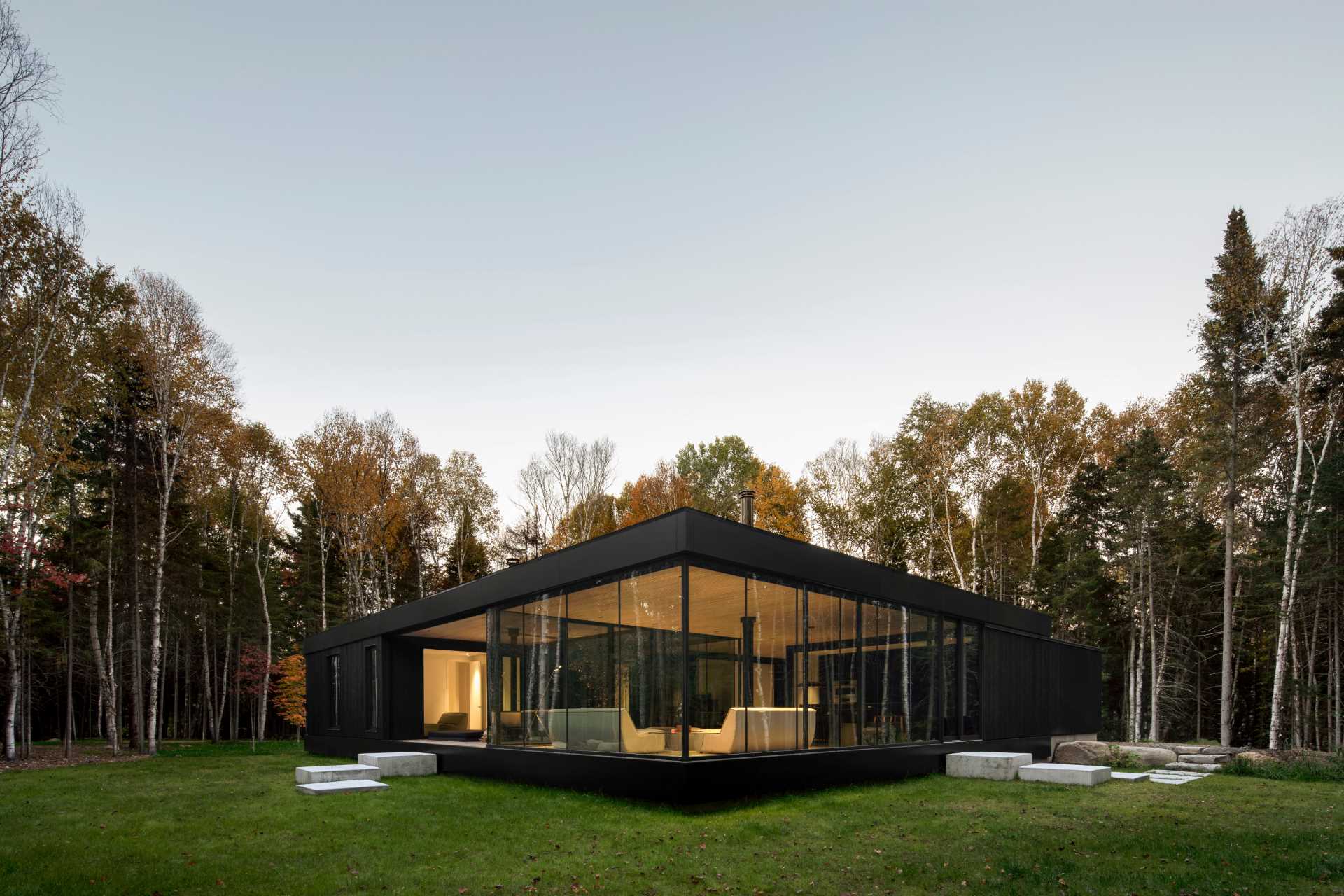 A modern black house exterior with floor-to-ceiling windows.