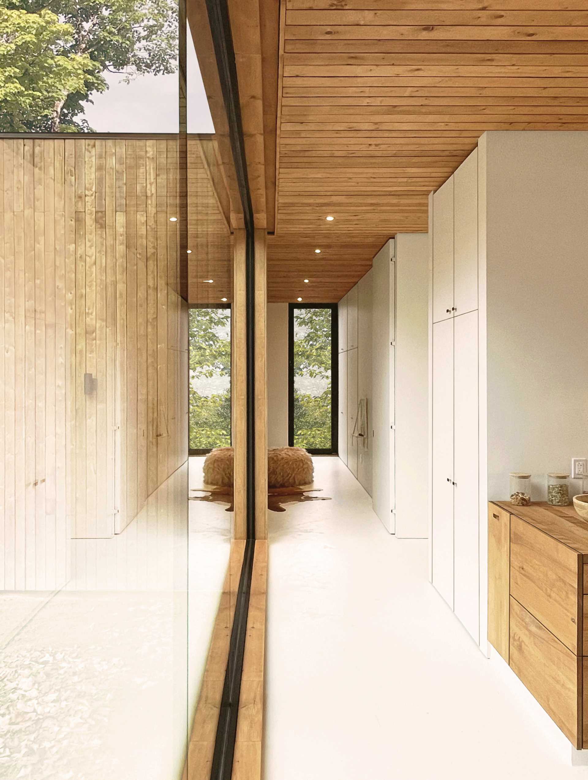 A modern house with a hallway lined with windows and storage cabinets.