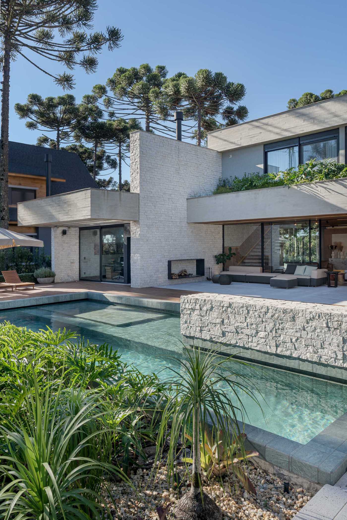 A modern home with a swimming pool, patio, and wood deck.